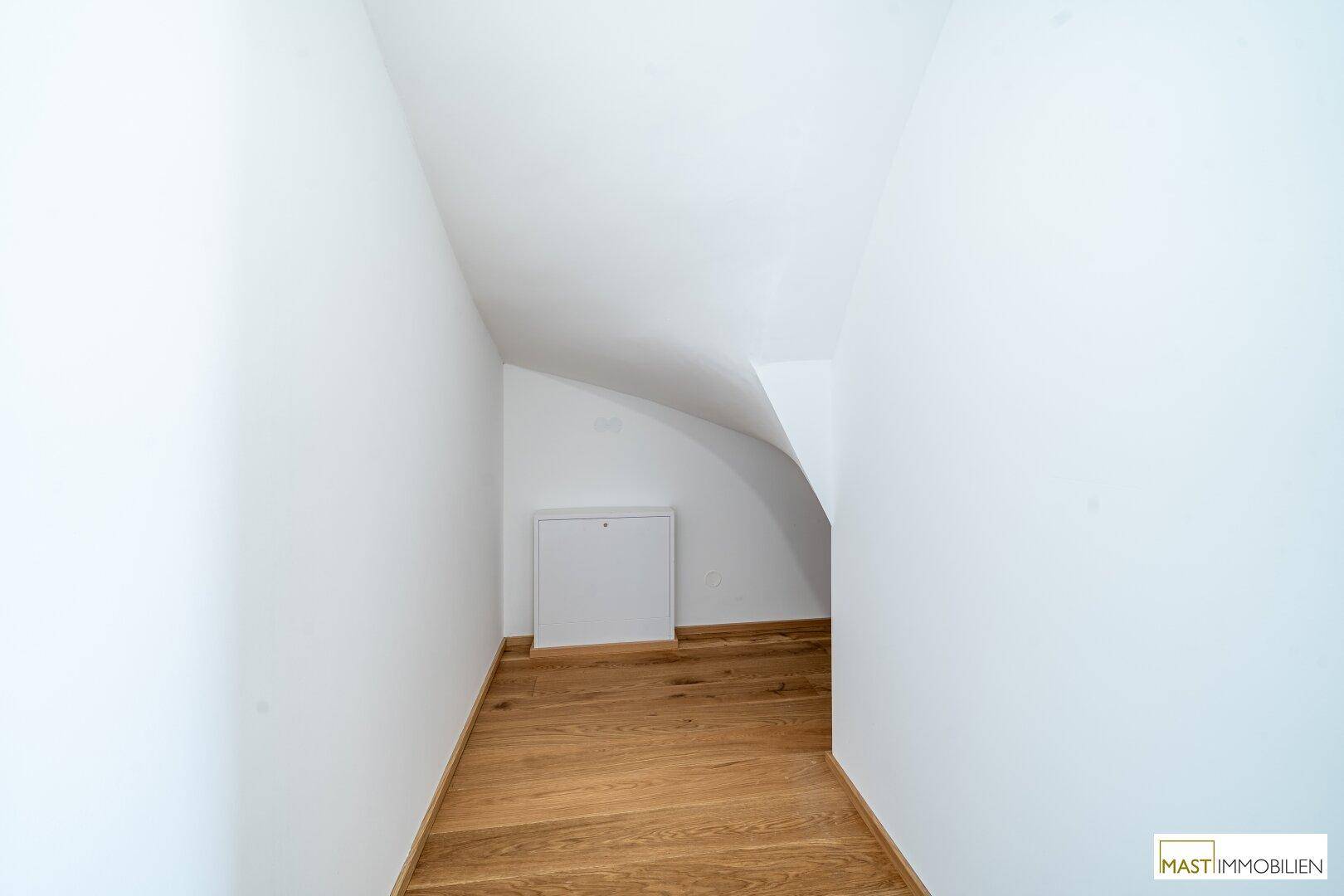 Praktischer Abstellraum mit Dachschräge und Holzfußboden für zusätzlichen Stauraum.