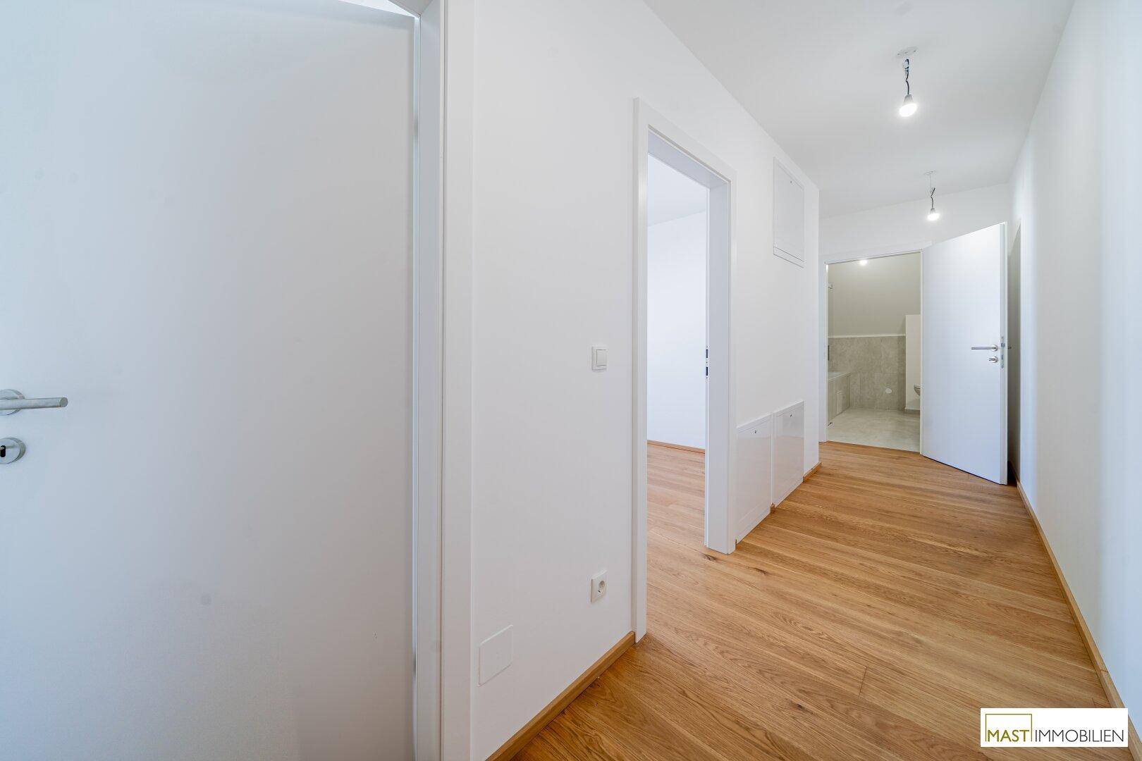 Heller Flur mit Holzfußboden und mehreren Türen, die zu den angrenzenden Räumen führen.