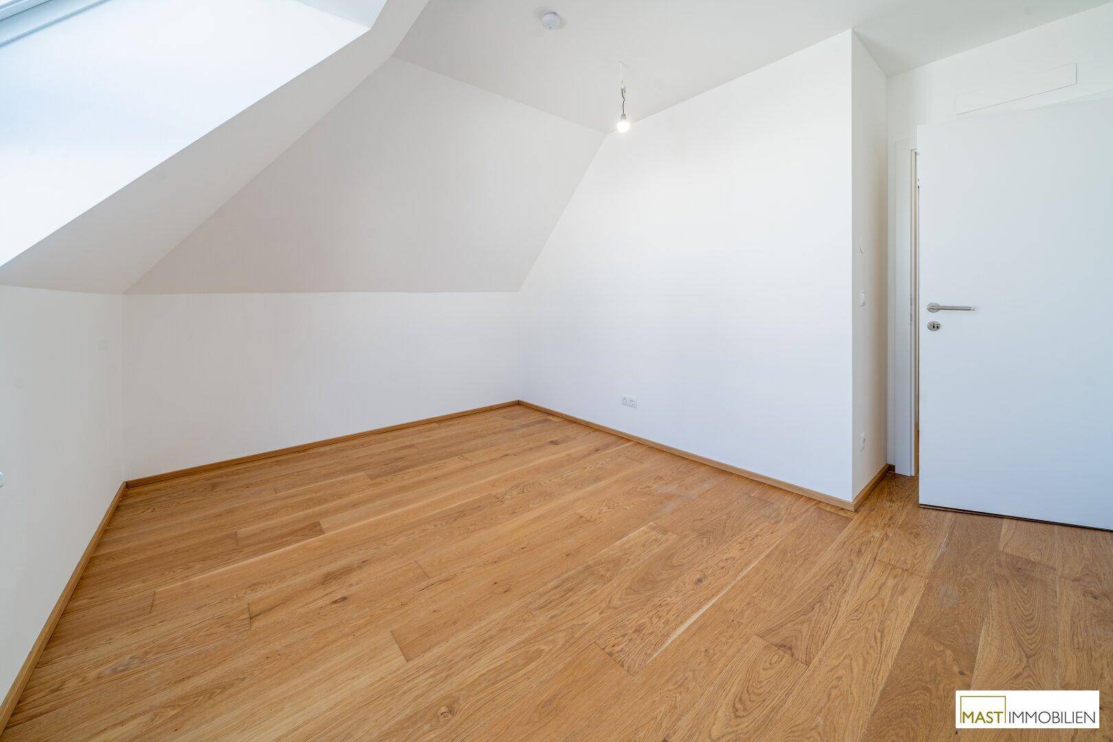 Schlafzimmer im Dachgeschoss mit Holzfußboden und schräger Decke, bietet viel Potenzial.