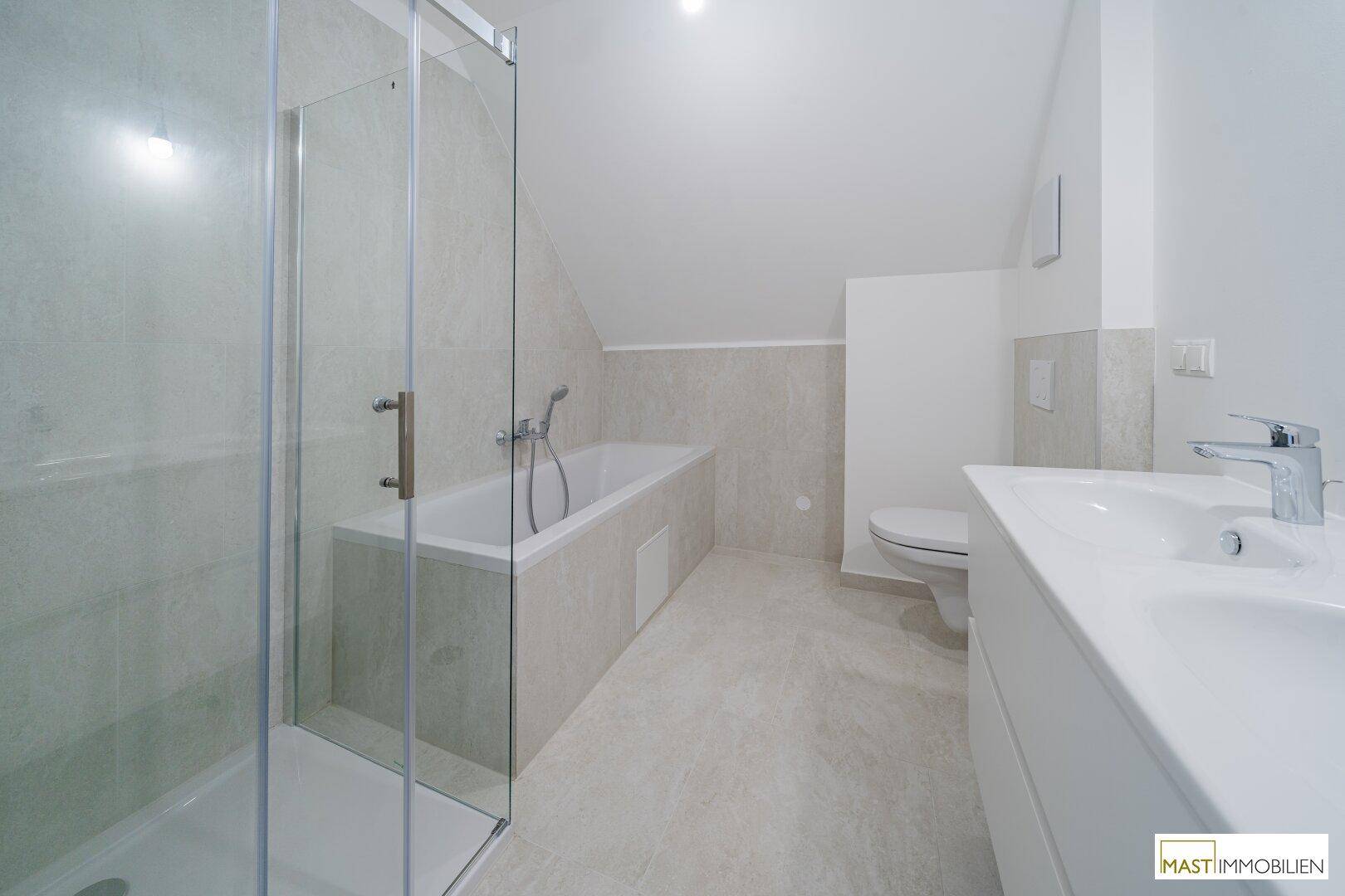 Modernes Badezimmer mit Dusche, Badewanne, WC und Einzelwaschbecken unter Dachschräge.