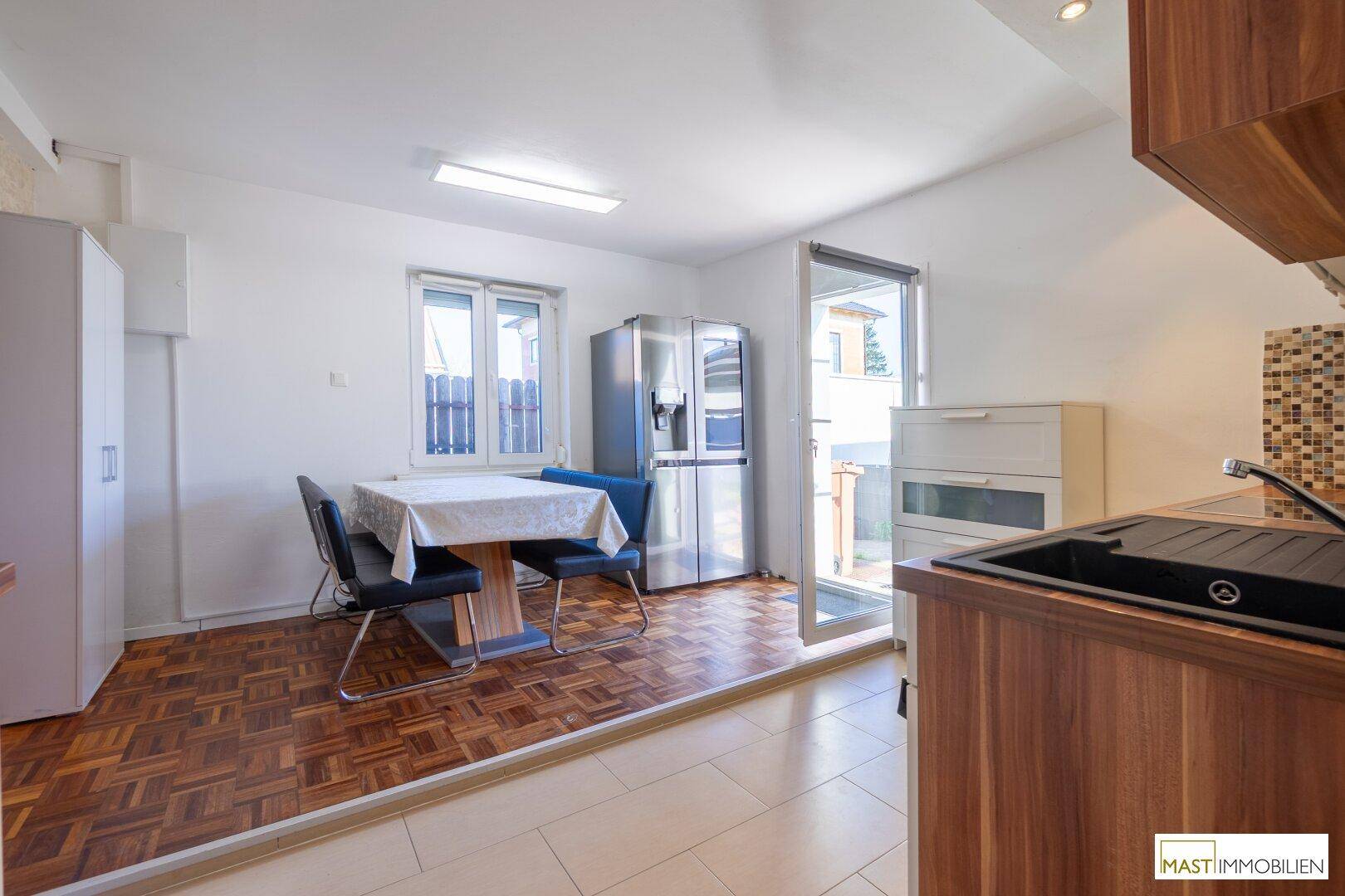 Gemütliche Wohnküche mit Essplatz, Kühlschrank und Zugang zu einem Außenbereich.