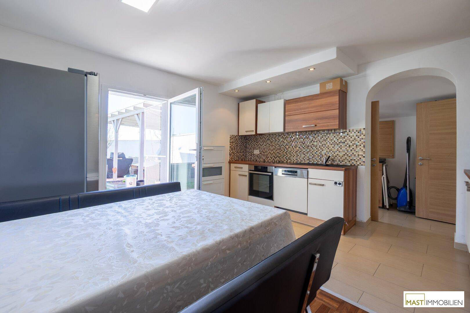 Helle Küche mit Essbereich, modernen Einbauschränken und direktem Zugang zur Terrasse.