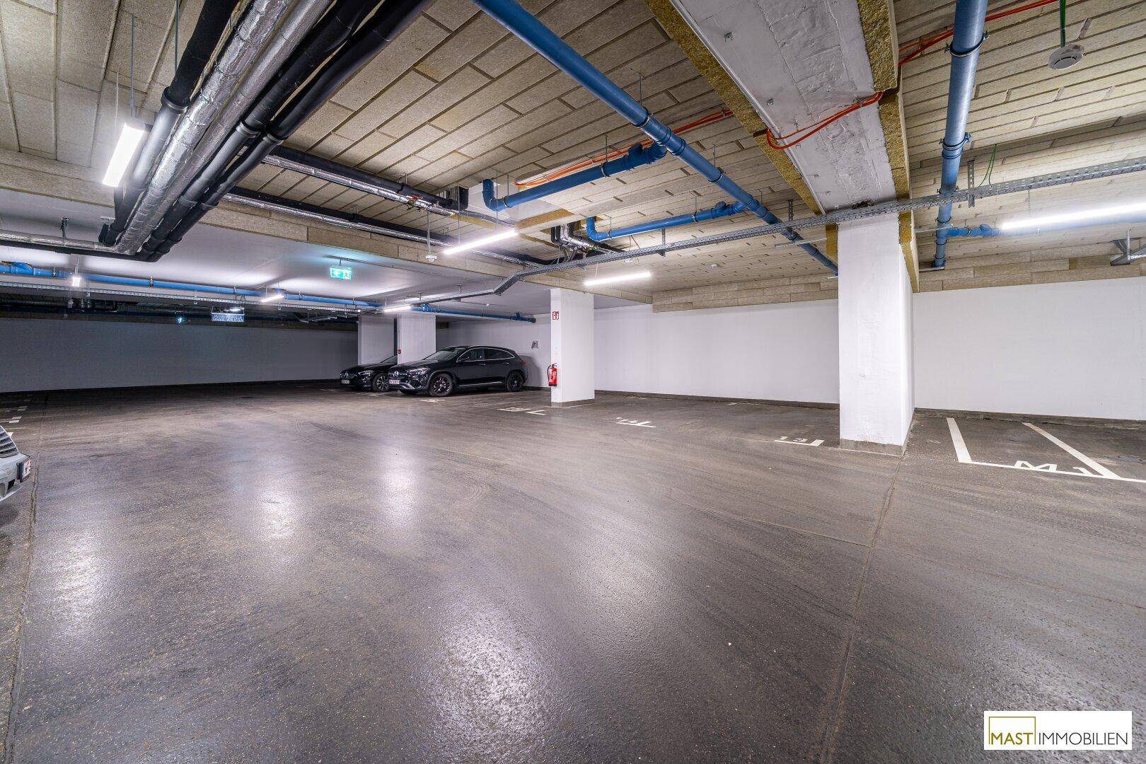 Helle Tiefgarage mit zahlreichen markierten Stellplätzen und guter Beleuchtung.