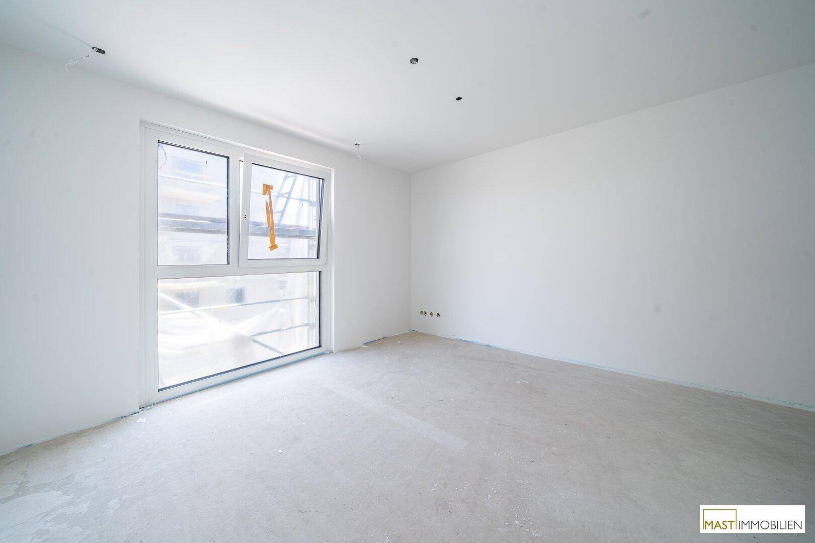 Unfertiges Schlafzimmer in einem Neubau mit großem Fenster und viel natürlichem Licht.
