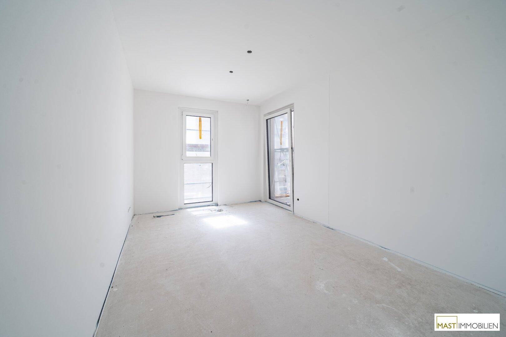 Unfertiges Schlafzimmer in einem Neubau mit zwei Fenstern und viel natürlichem Licht.