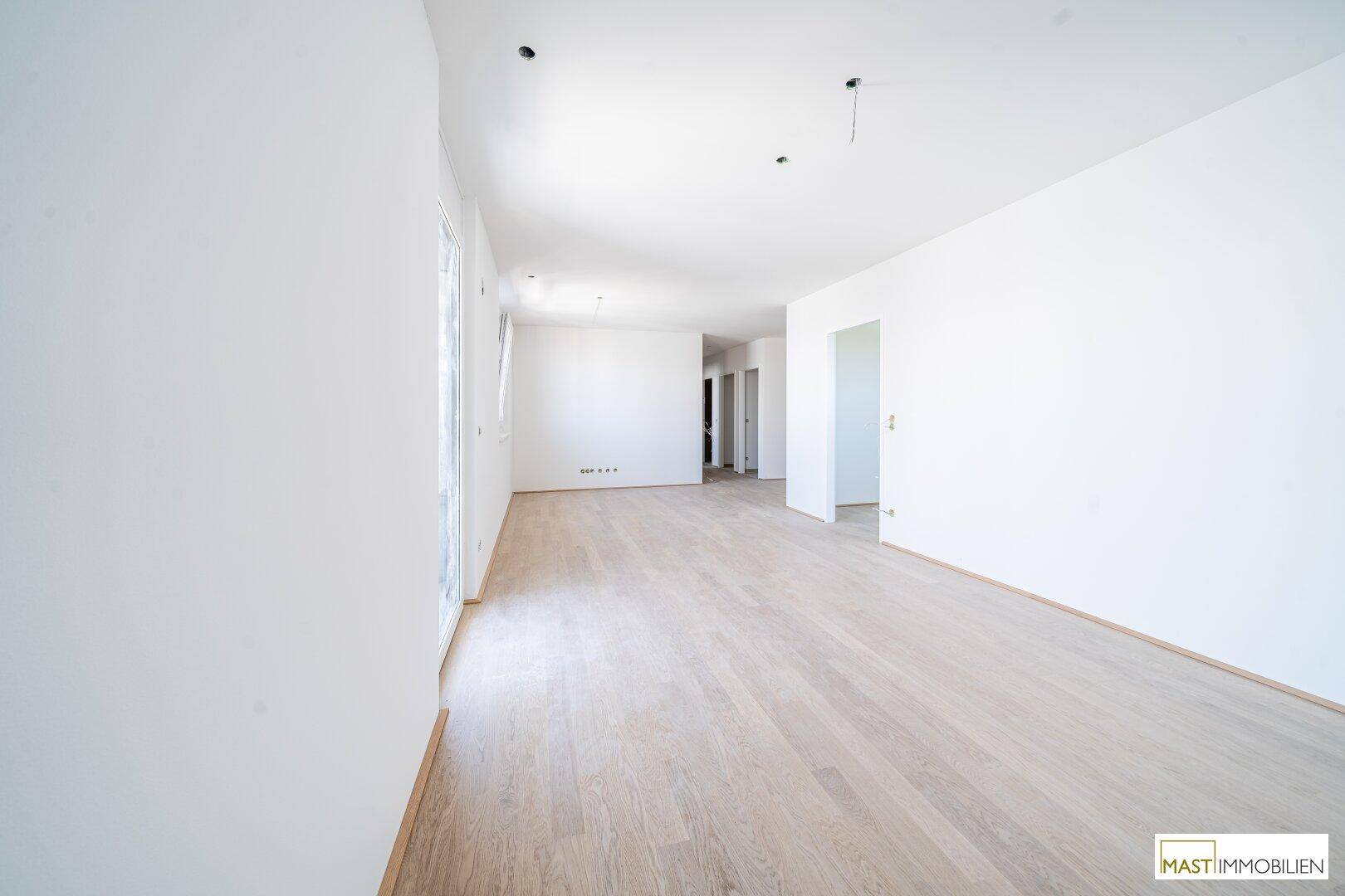 Großer, heller Wohnbereich mit Parkettboden und Zugang zu einem französischen Balkon, ideal für Gestaltung.