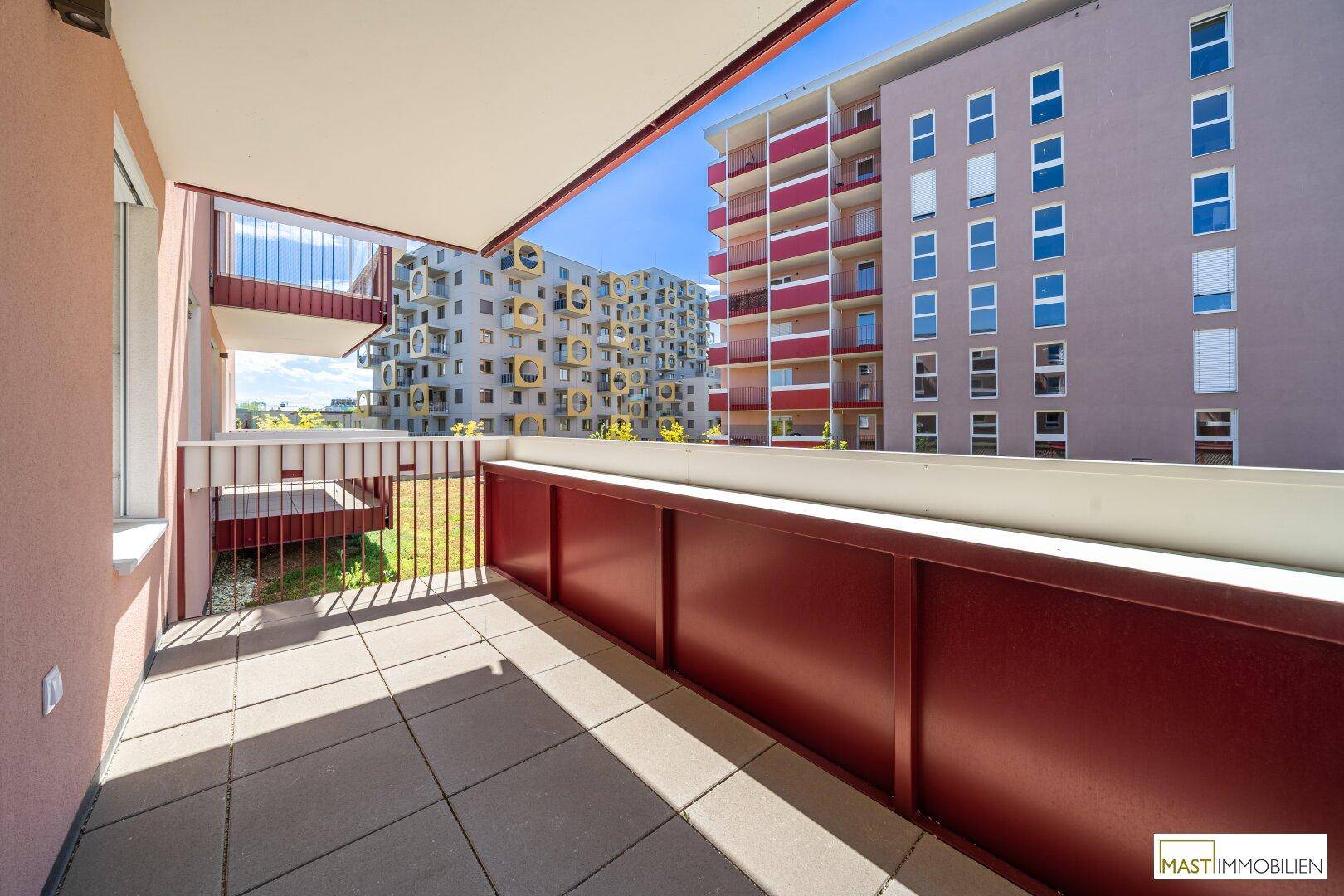 Großer Balkon mit Fliesenboden und weitem Blick auf die moderne Wohnbebauung.