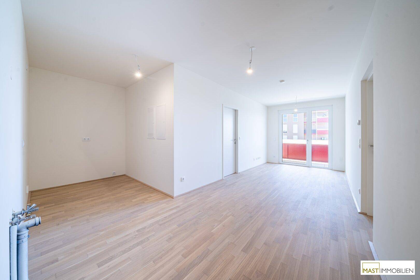 Geräumiger, heller Wohnbereich mit Parkettboden und direktem Zugang zum Balkon.