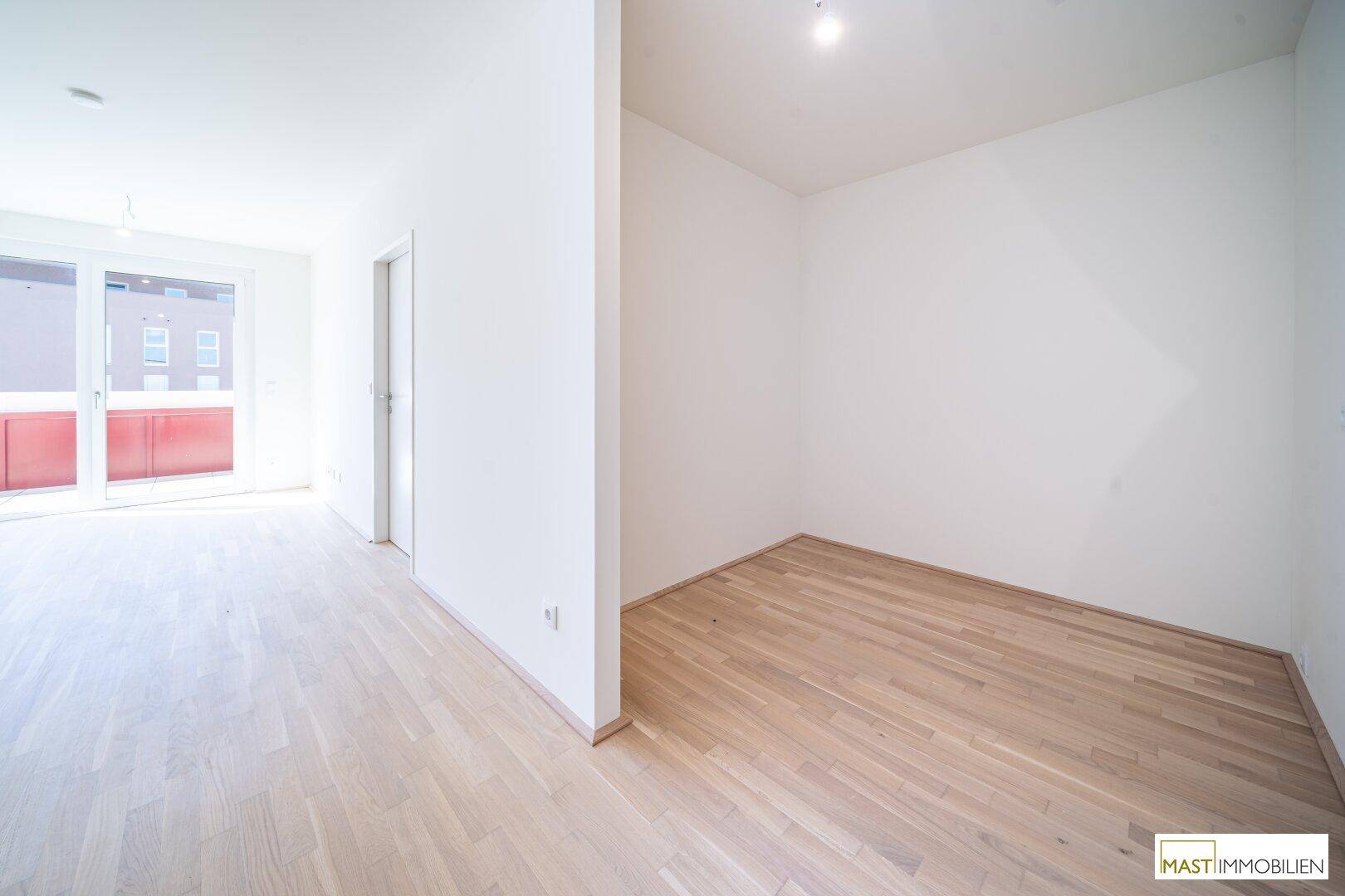 Lichtdurchfluteter Wohnbereich mit neuem Parkettboden und weiß gestrichenen Wänden.