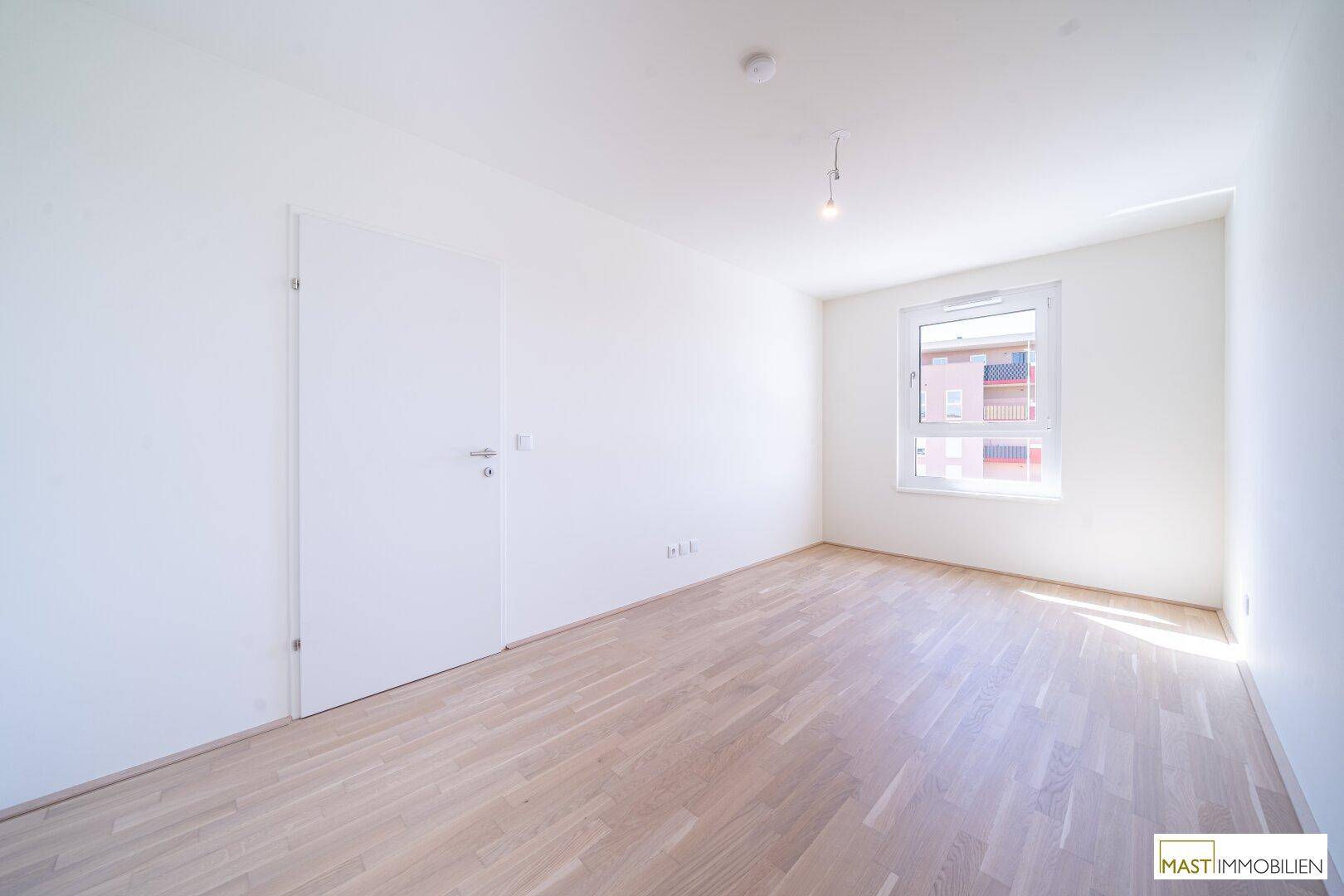 Leeres Schlafzimmer mit Parkettboden und Fenster, bereit zur individuellen Gestaltung.