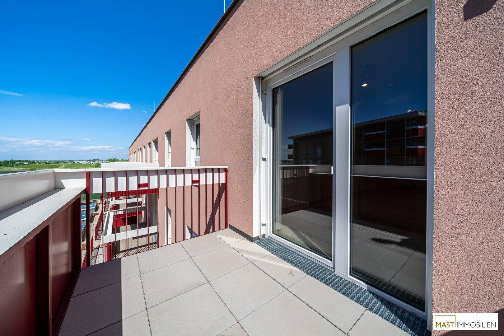 Sonnenverwöhnter Balkon mit Fliesenboden und Schiebetür, bietet einen schönen Ausblick auf die Umgebung.