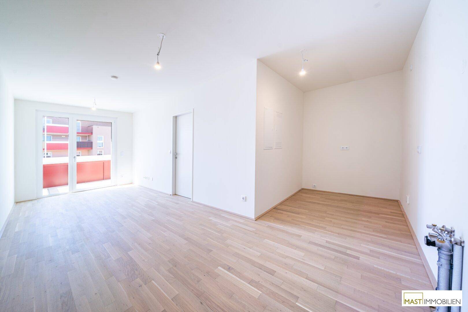 Heller, leerer Raum mit hellem Holzfußboden und Zugang zu einem Balkon, ideal für individuelle Gestaltung.