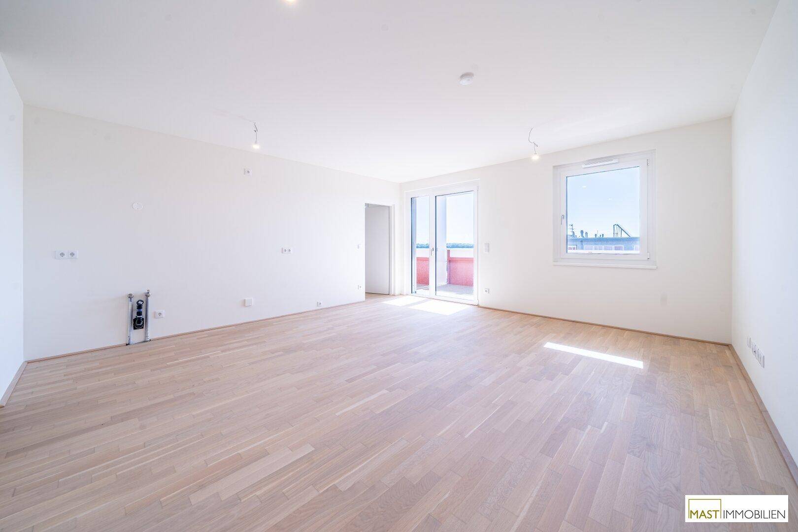 Großes, helles Wohnzimmer mit Eichenparkett und Zugang zu einem sonnigen Balkon.