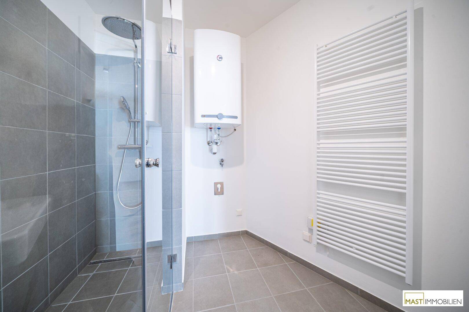 Funktionales Badezimmer mit begehbarer Dusche, Warmwasserbereiter und einem beheizten Handtuchhalter.