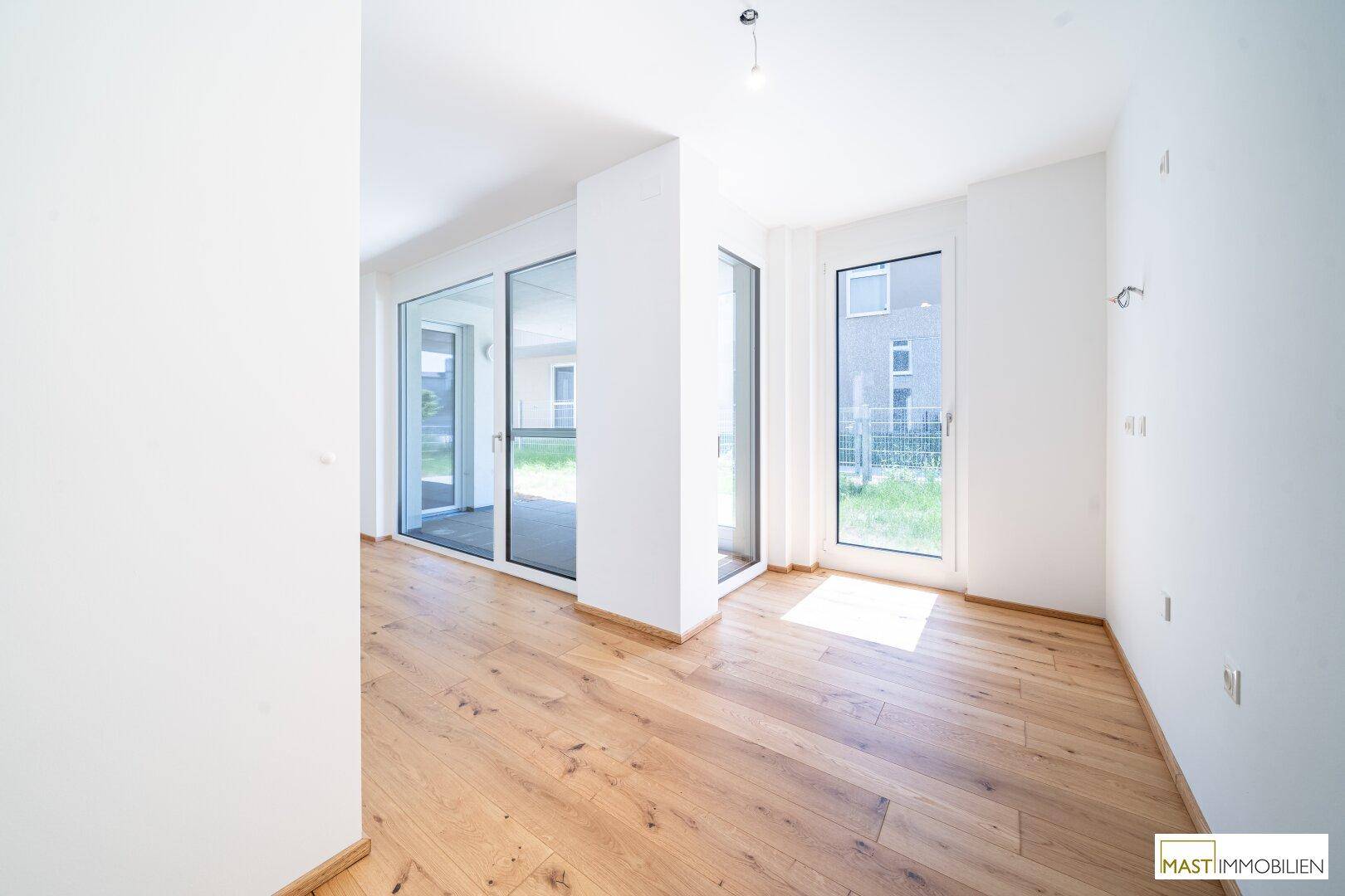Heller Wohnbereich mit mehreren Fenstern und Holzboden, bietet viel Tageslicht.