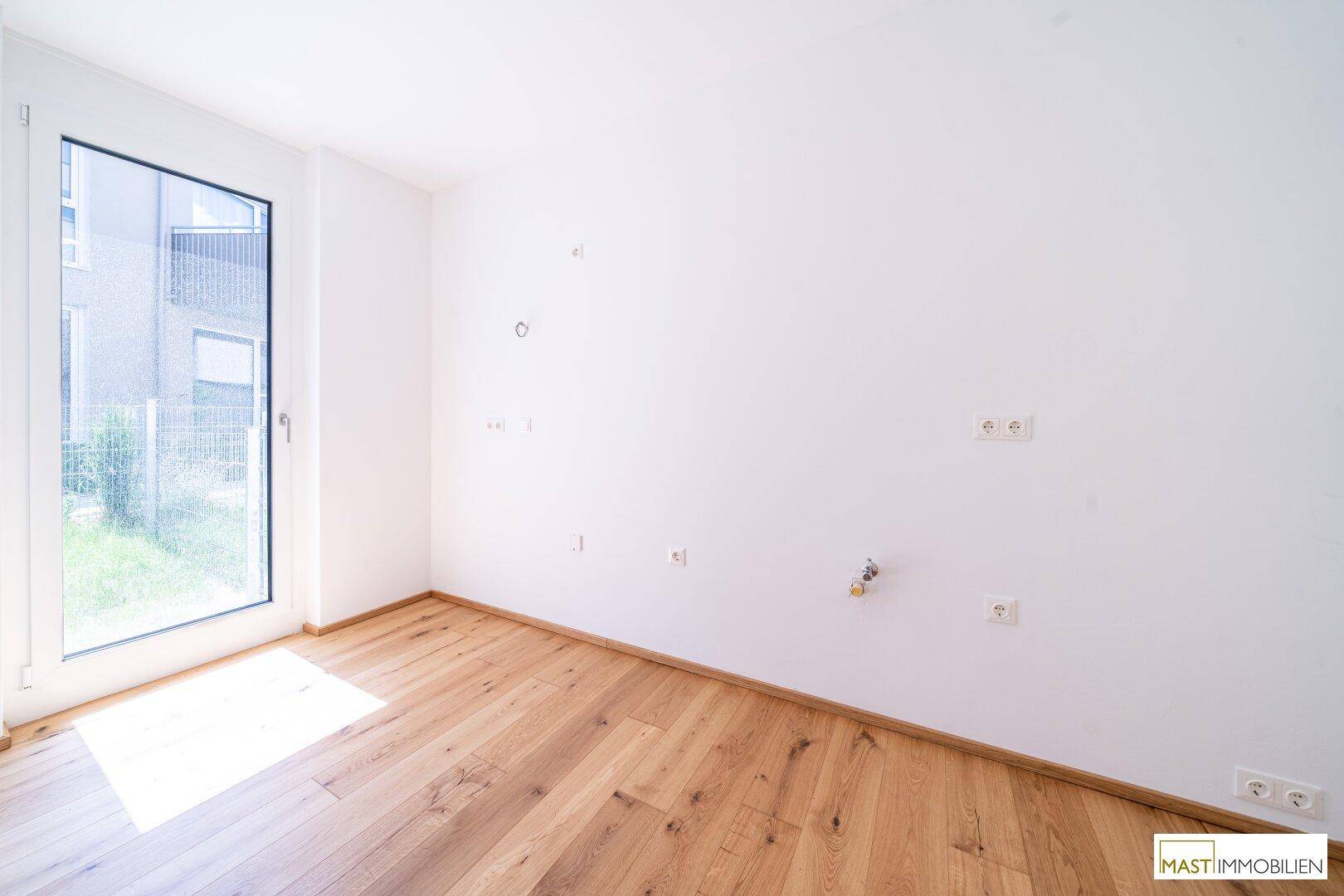 Kleiner Raum mit Holzboden und Anschlussmöglichkeiten, ideal für eine Küche oder Hauswirtschaftsraum.