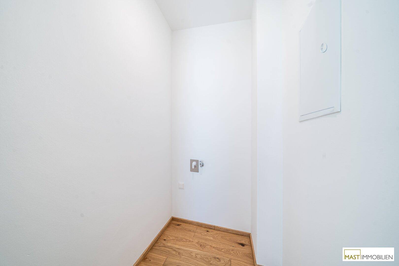 Kleiner Hauswirtschaftsraum mit Fliesenboden und Anschluss für eine Waschmaschine.