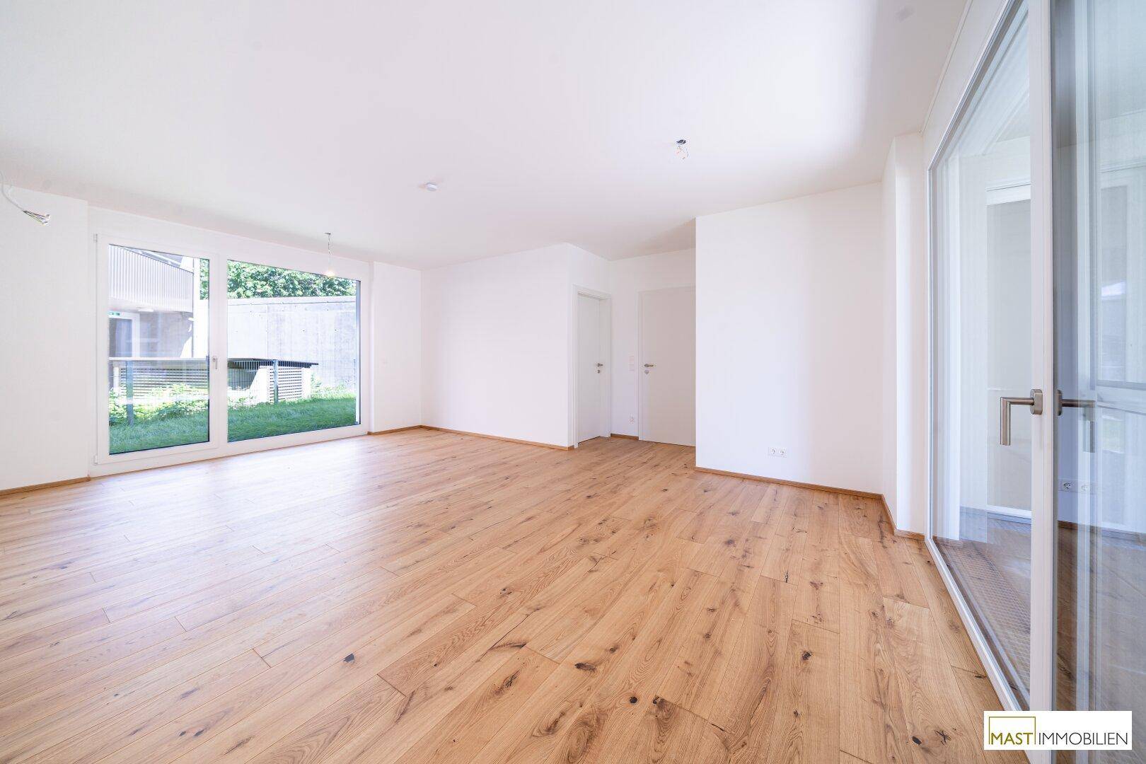 Lichtdurchflutetes Wohnzimmer mit Holzboden und Zugang zu einem Außenbereich.