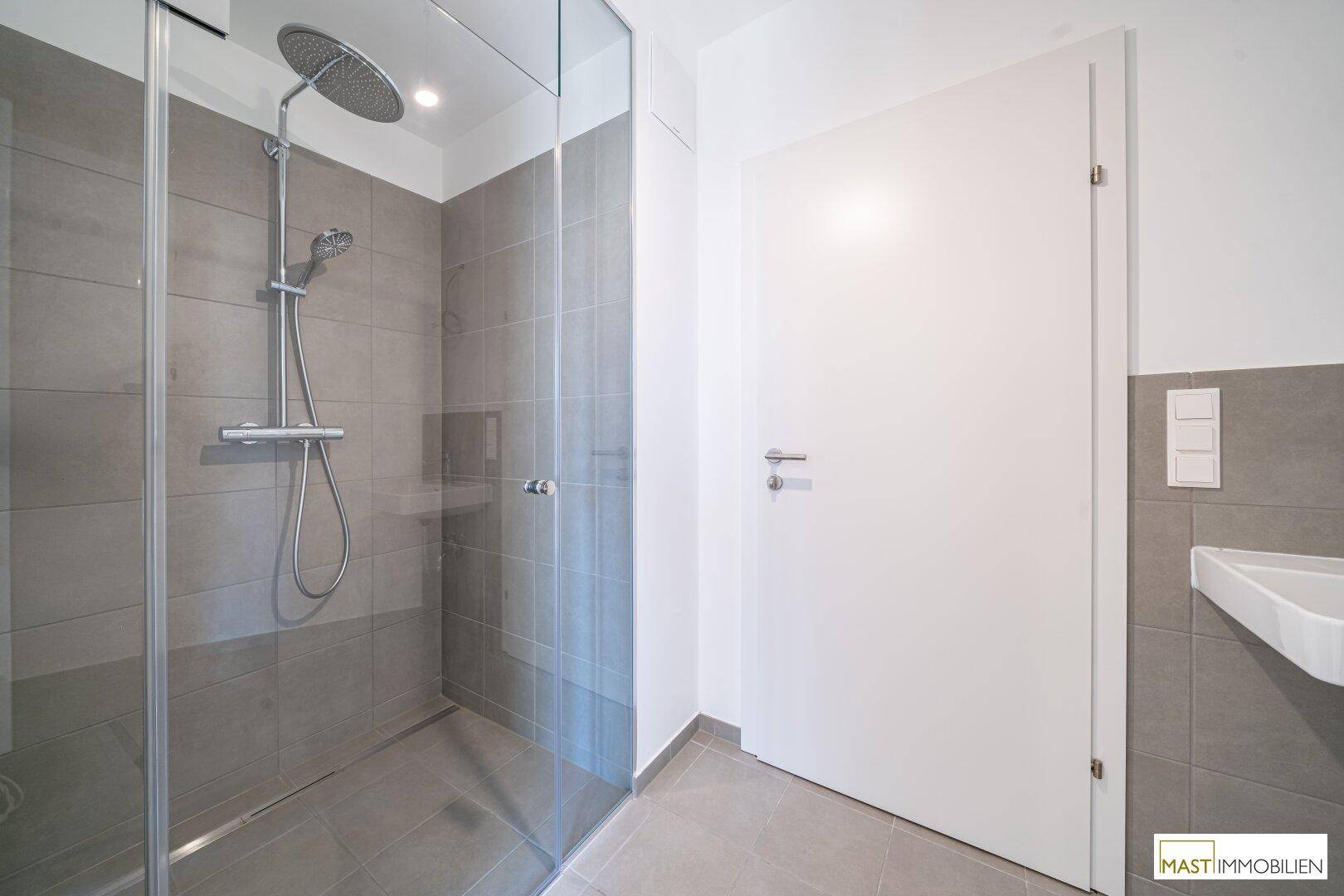 Modernes Badezimmer mit begehbarer Dusche, Regendusche und grauen Fliesen.