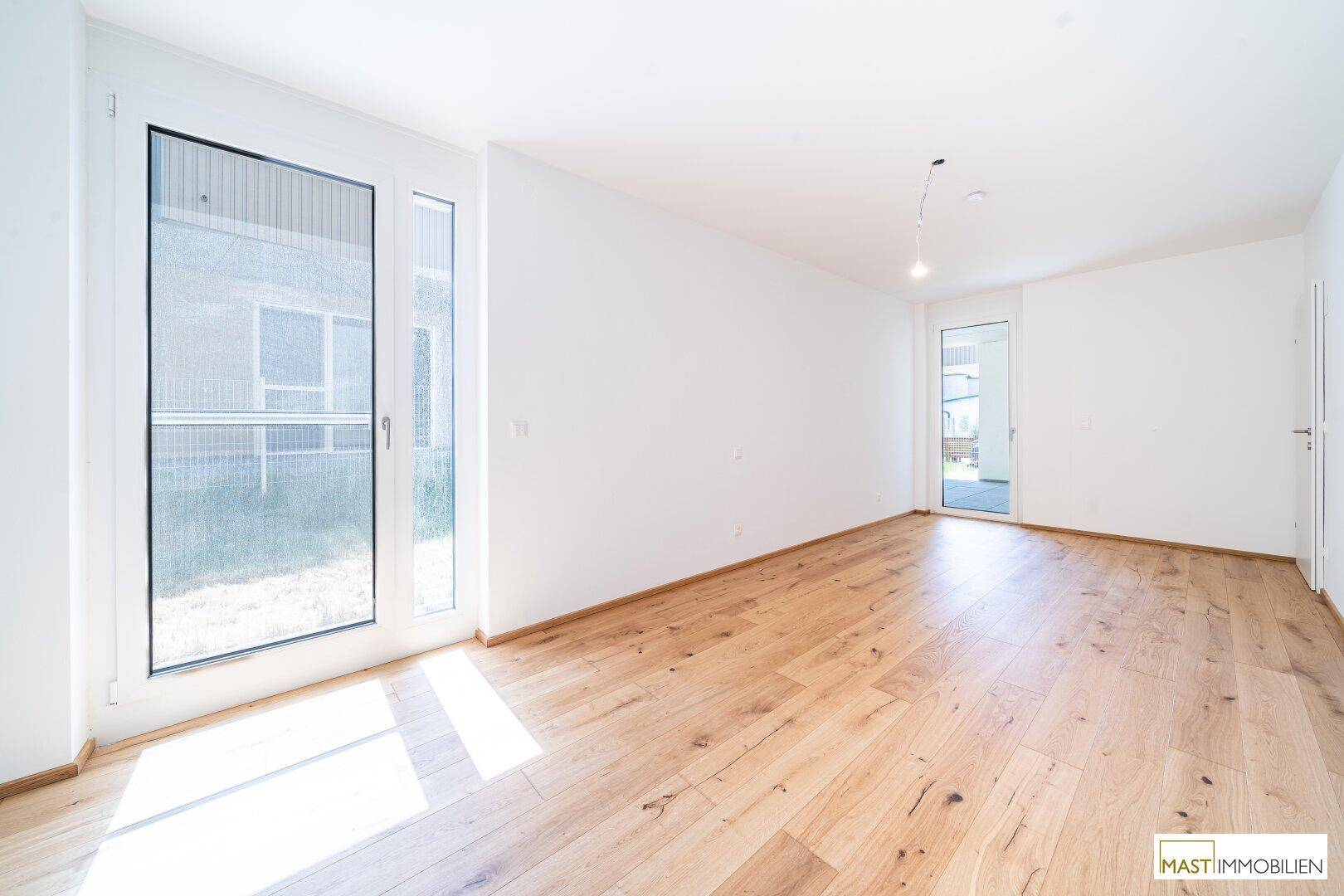 Geräumiges Schlafzimmer mit Holzboden und großen Fenstern, bietet viel Tageslicht.