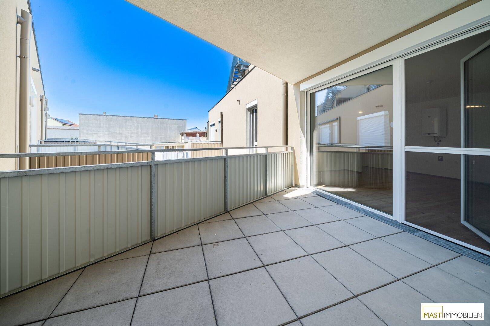 Geräumiger Balkon mit Fliesenboden und Metallgeländer, bietet Platz für Entspannung im Freien.