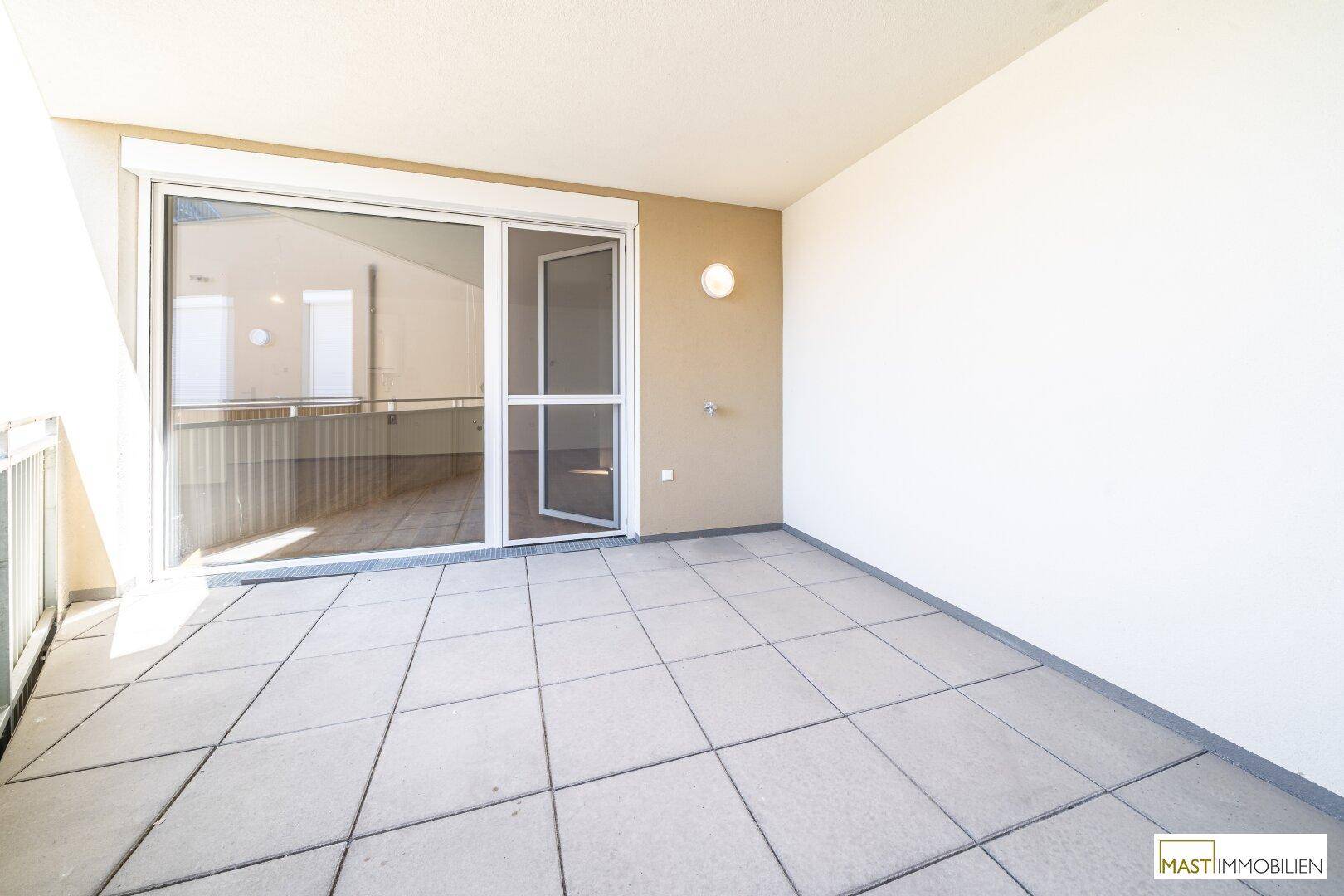 Heller Balkon mit Fliesenboden und Blick auf die Umgebung, ideal für sonnige Stunden.