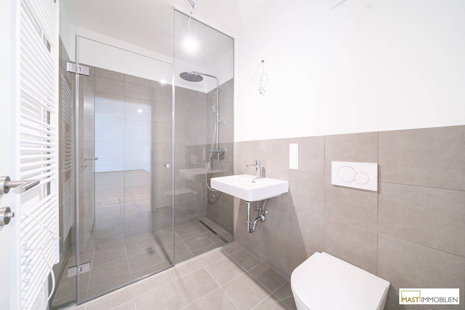 Modernes Badezimmer mit begehbarer Dusche, Wand-WC und grauen Fliesen.