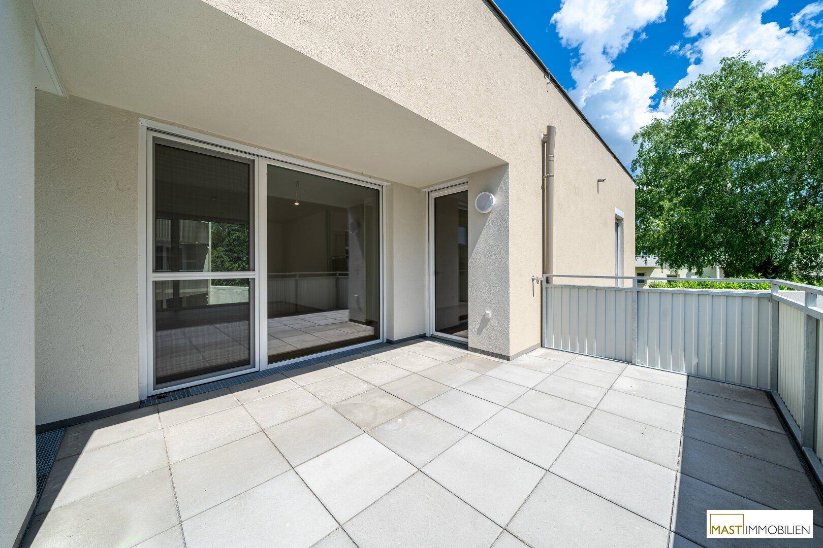 Geräumige Terrasse mit Fliesenboden und Zugang zum Innenbereich, ideal für entspannte Stunden im Freien.