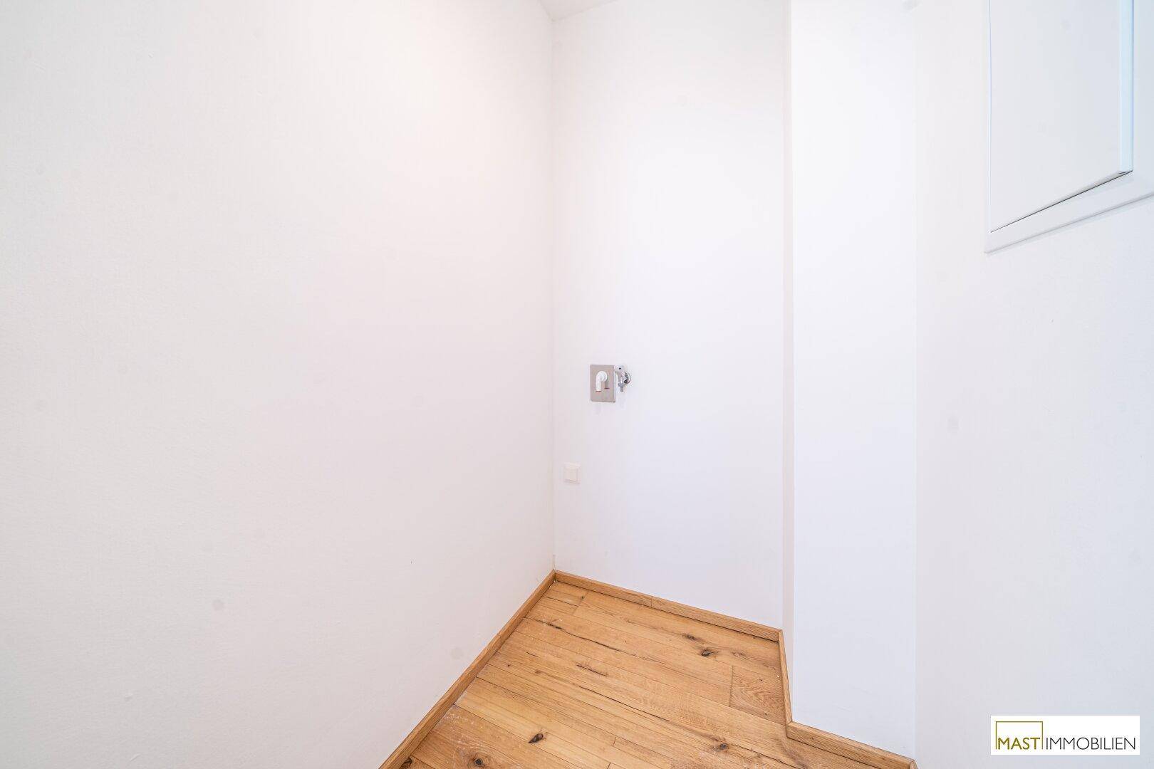 Kleiner Abstellraum mit Holzboden und weißen Wänden, ideal für Lagerzwecke oder Haustechnik.
