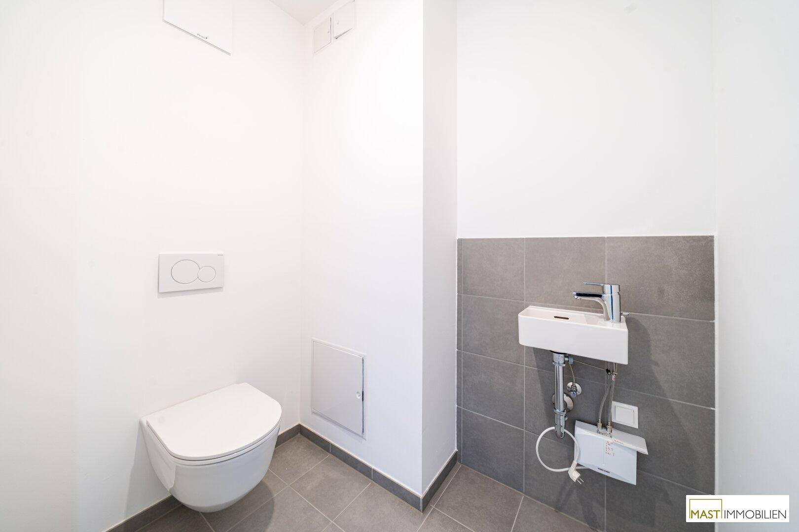 Modernes Gäste-WC mit wandhängender Toilette und kleinem Waschbecken.