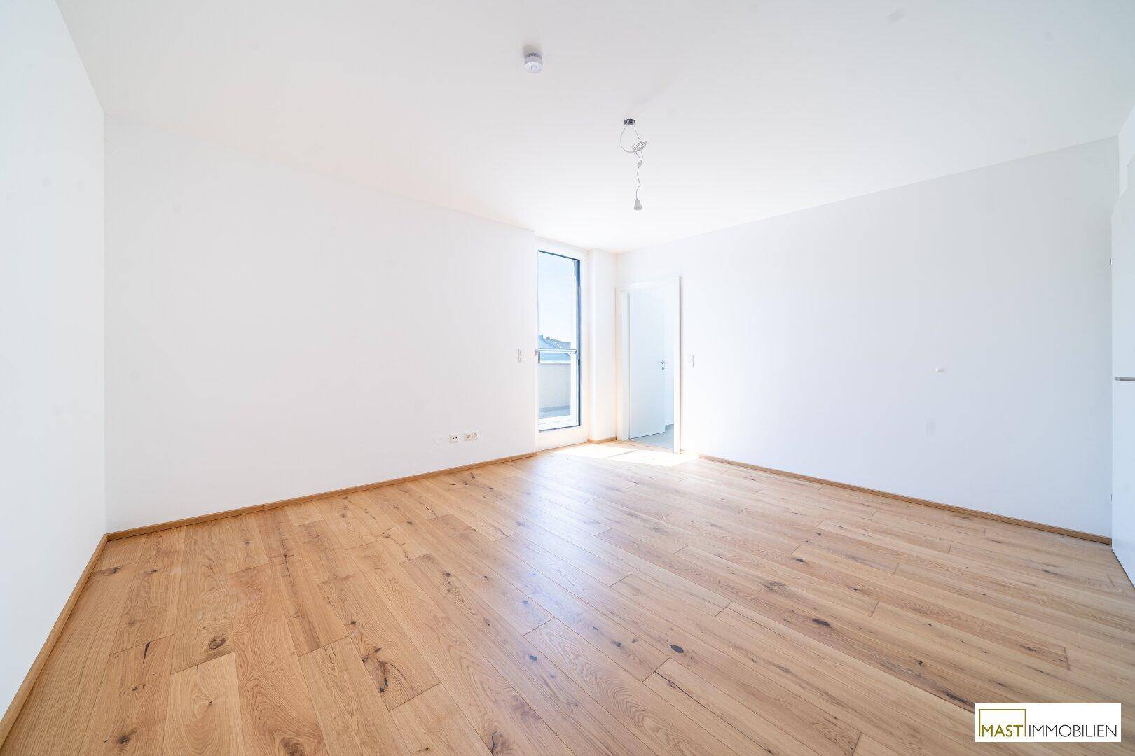 Lichtdurchflutetes Zimmer mit Holzboden und Zugang zu einem Außenbereich, bereit zur Einrichtung.