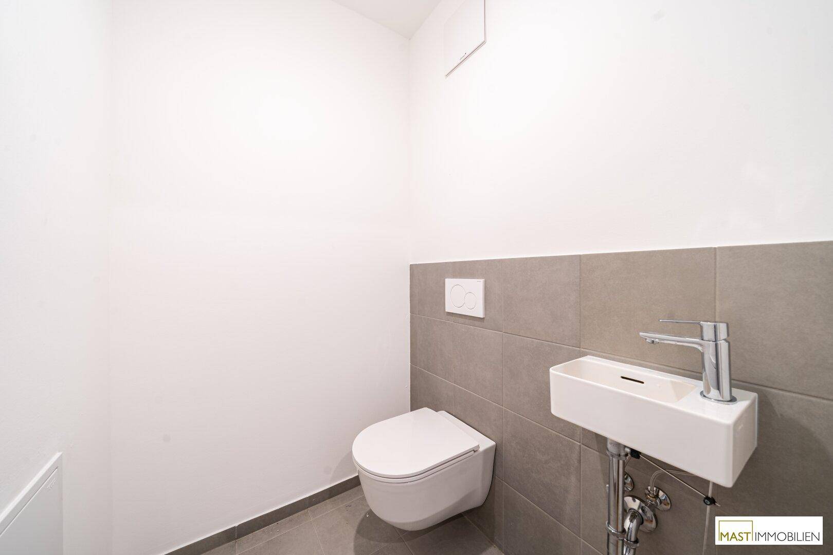 Modernes Gäste-WC mit wandhängender Toilette und kleinem Waschbecken.