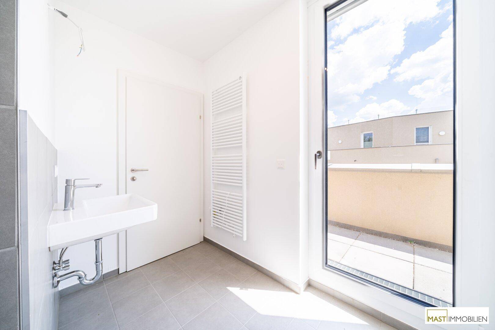 Helles Badezimmer mit modernem Waschbecken, Handtuchheizkörper und Fenster.