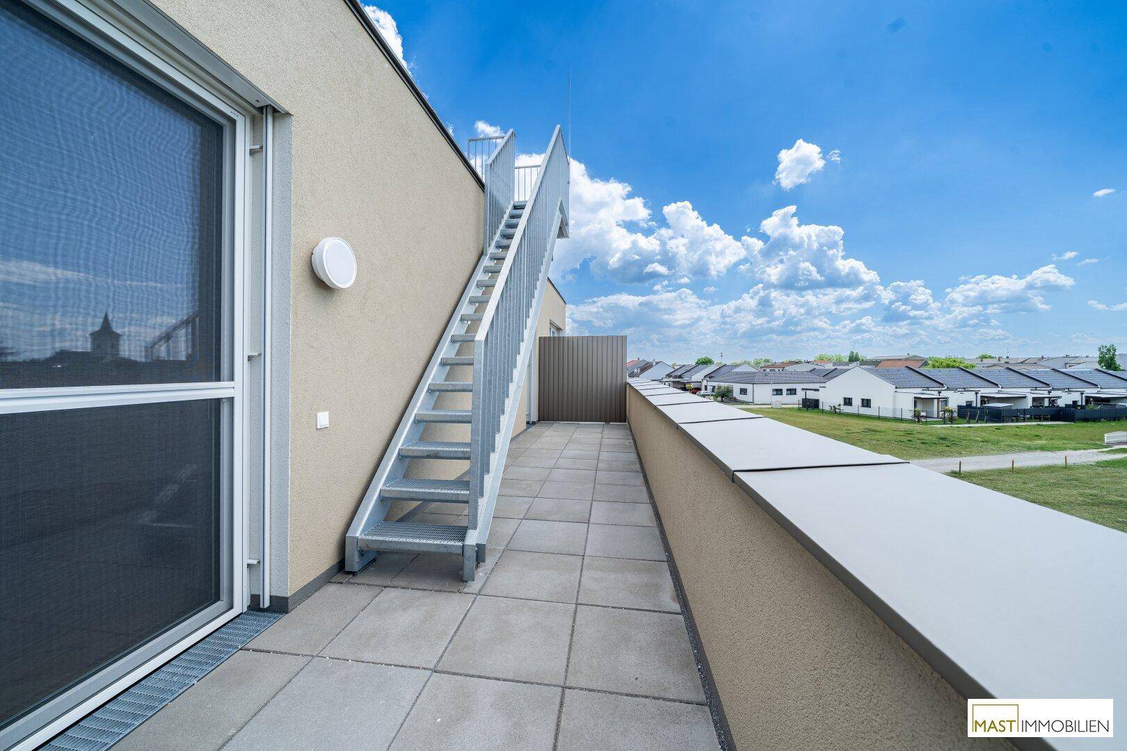 Dachterrasse mit Außentreppe zum oberen Bereich und Blick auf die umliegende Wohnbebauung.