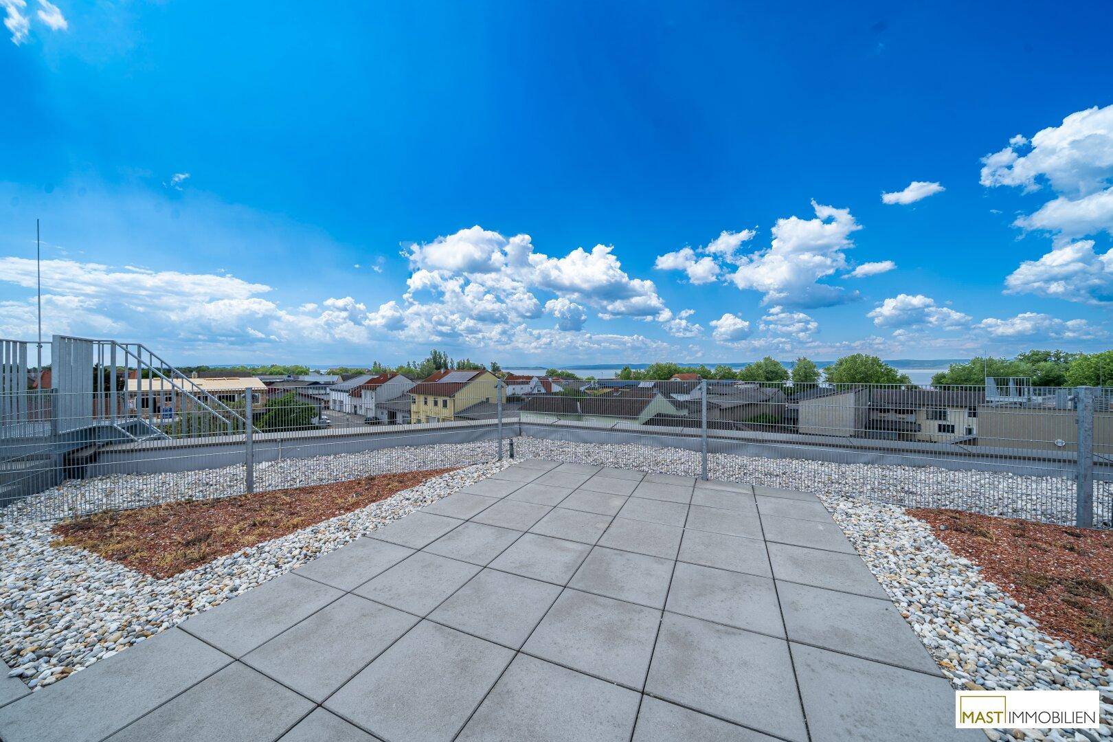 Gepflasterter Bereich auf der Dachterrasse mit Panoramablick auf den See und die Umgebung.