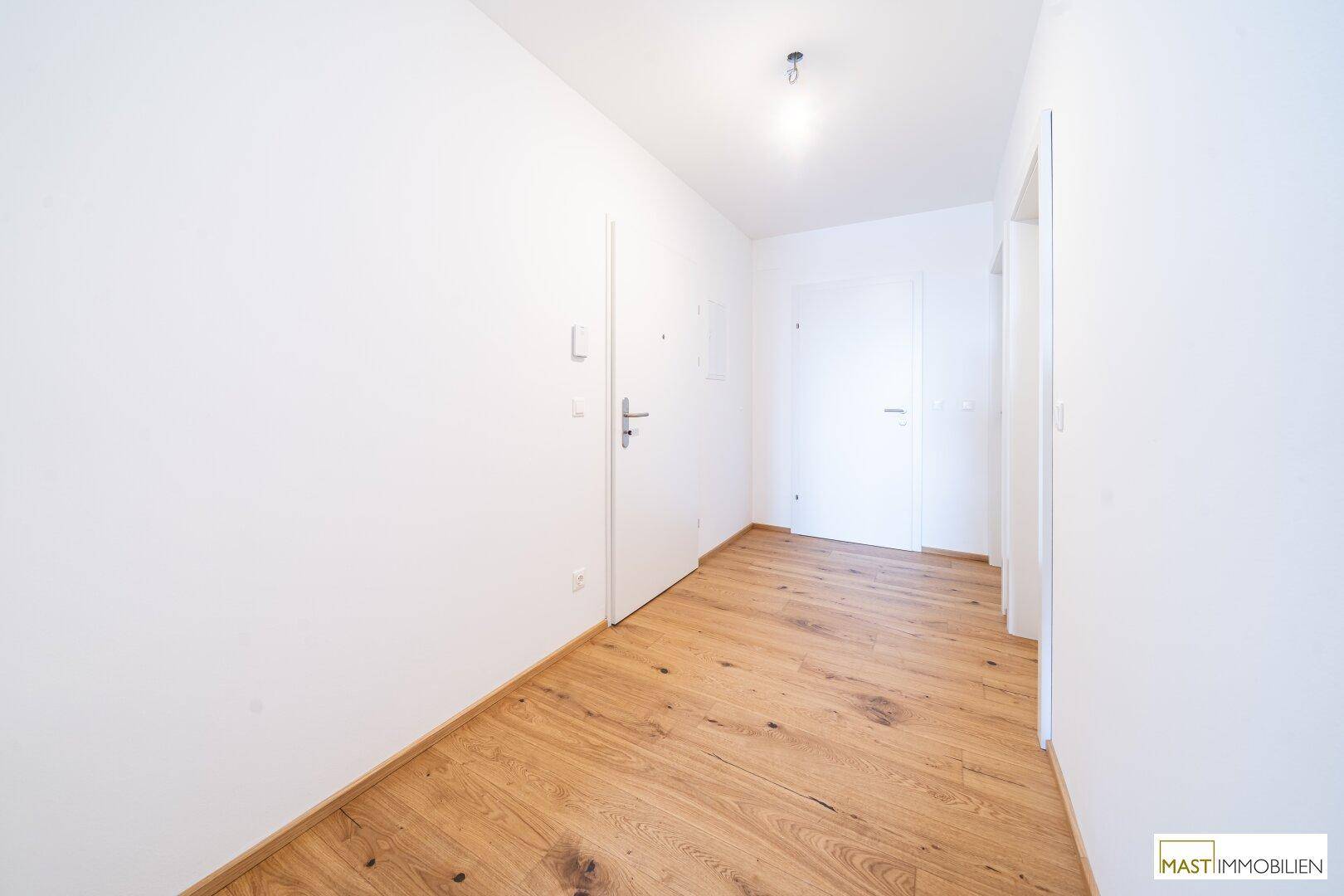 Heller Flur mit Holzboden und weißen Türen, der zu den verschiedenen Räumen führt.