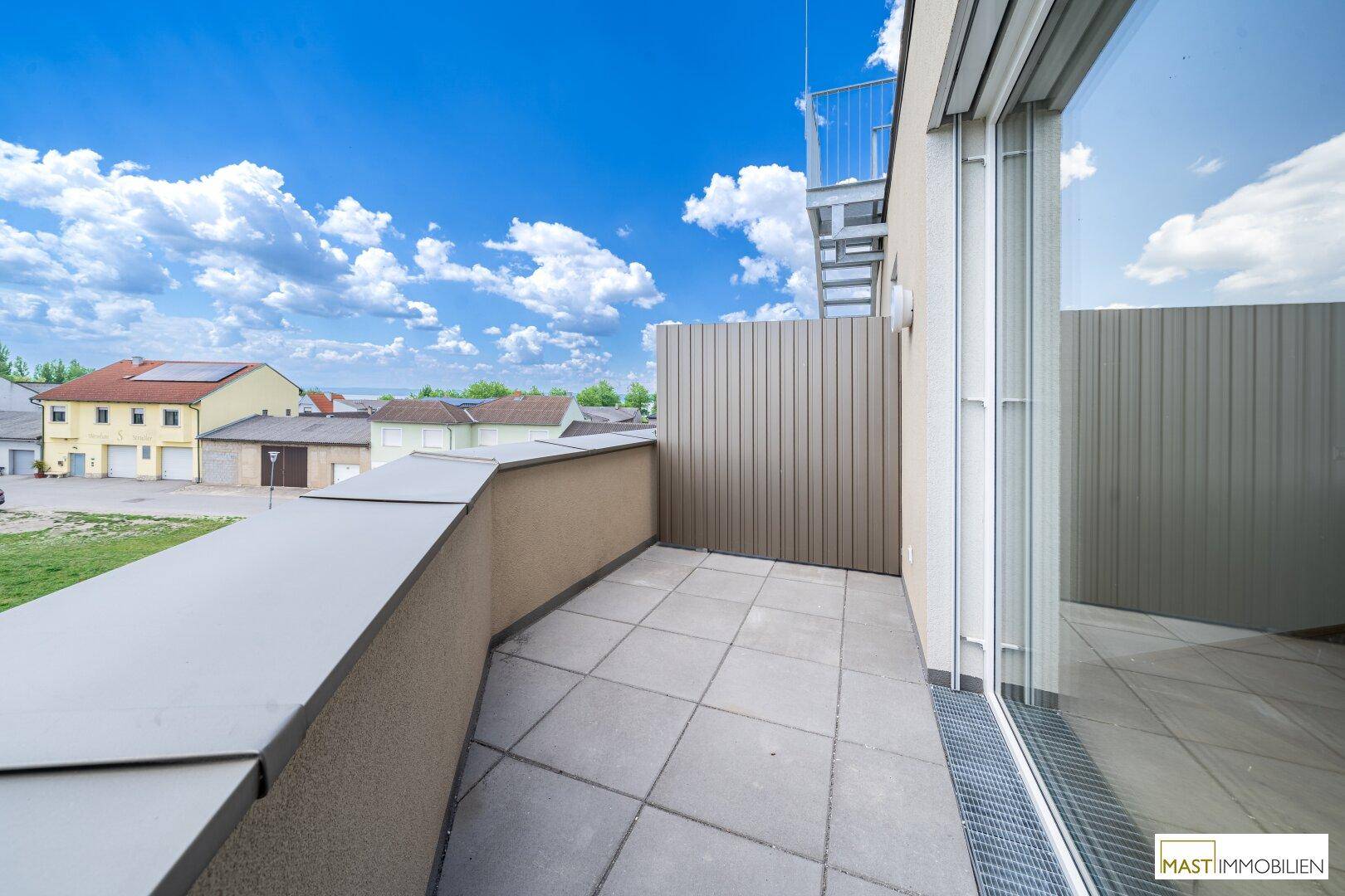 Geräumiger Balkon mit Fliesenboden und Blick auf die umliegende Wohngegend.