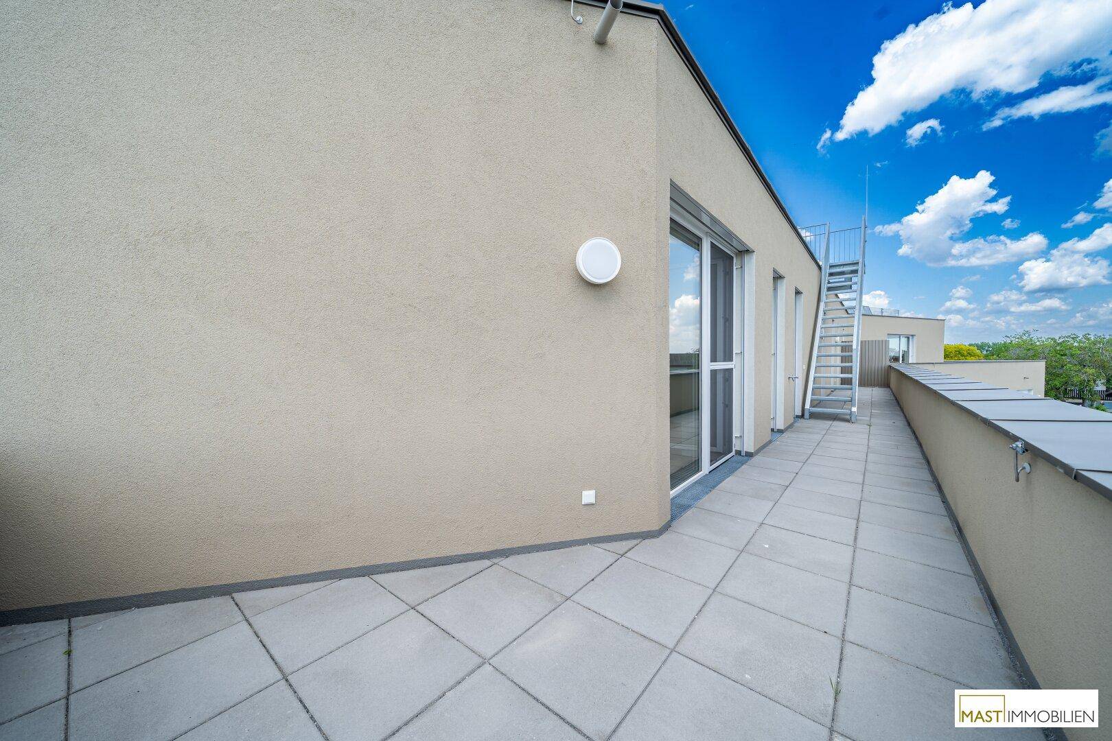 Große Terrasse mit Fliesenboden und Zugang zu den Innenräumen, ideal für Entspannung.