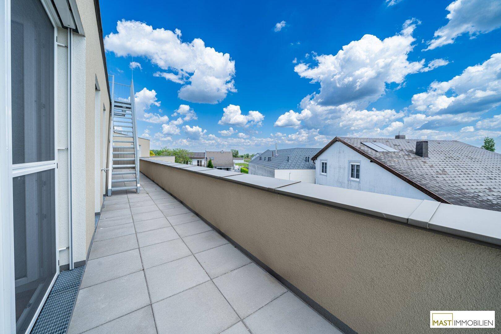 Weitläufige Terrasse mit Fliesenboden und Ausblick auf die Dächer der Nachbarschaft.