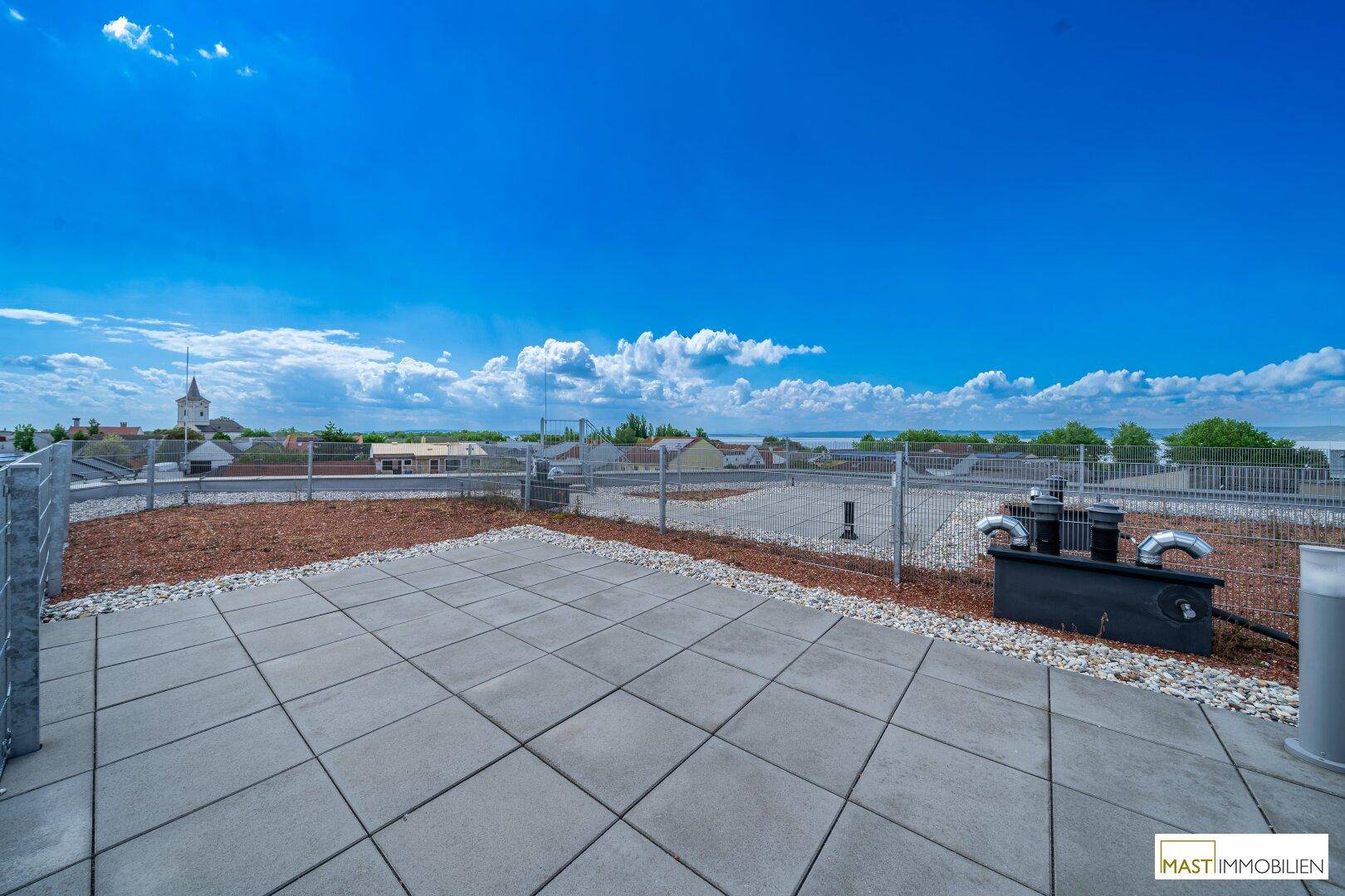 Dachterrasse mit Fliesen und Kies, bietet einen weiten Blick über die Stadt und den See.