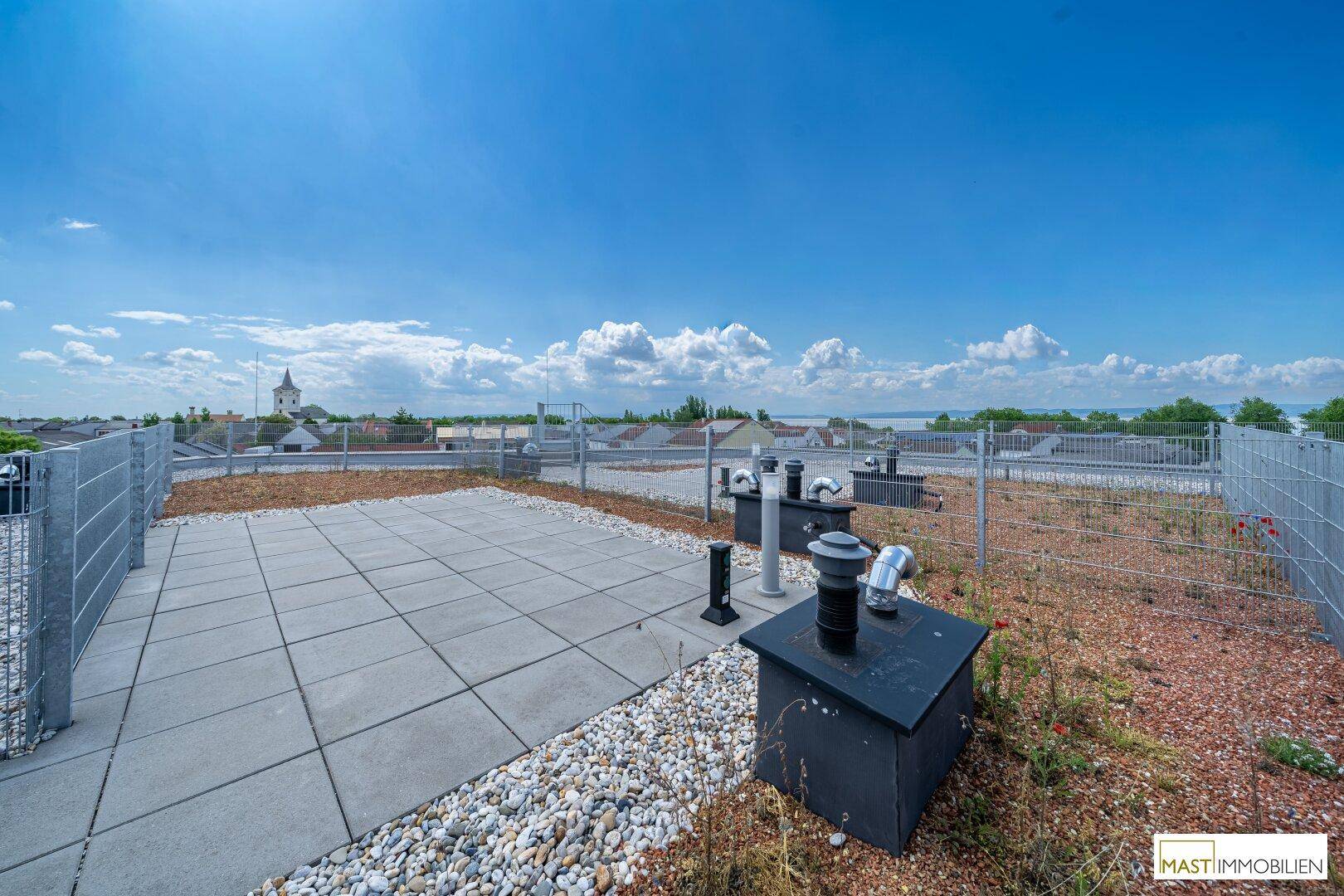 Weitläufige Dachterrasse mit Kies und Fliesen, ideal für Entspannung mit Panoramablick.