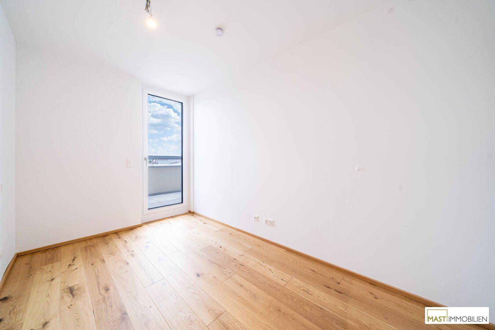 Ruhiges Schlafzimmer mit Holzboden und Zugang zu einem kleinen Balkon oder einer Terrasse.