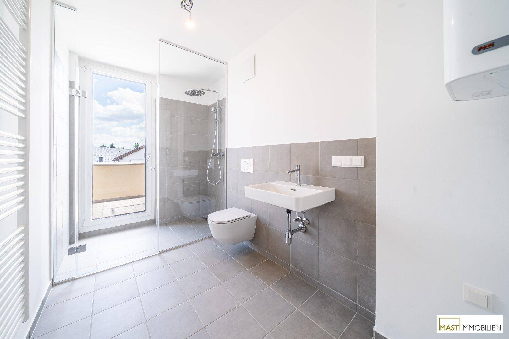 Modernes Badezimmer mit ebenerdiger Dusche, Wand-WC und beheiztem Handtuchhalter.