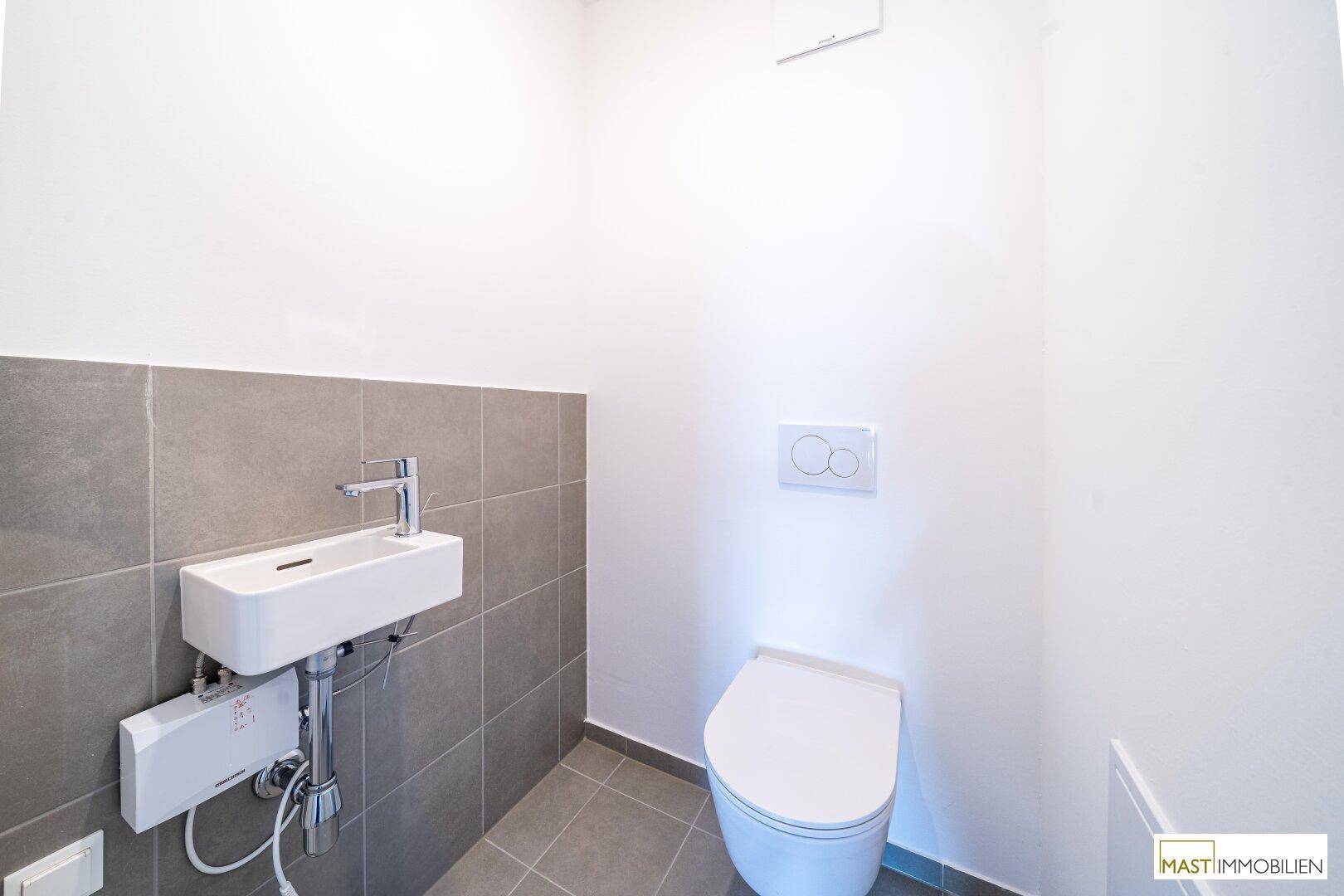 Kleines Gäste-WC mit modernem Wand-WC und Handwaschbecken, in schlichtem Design.