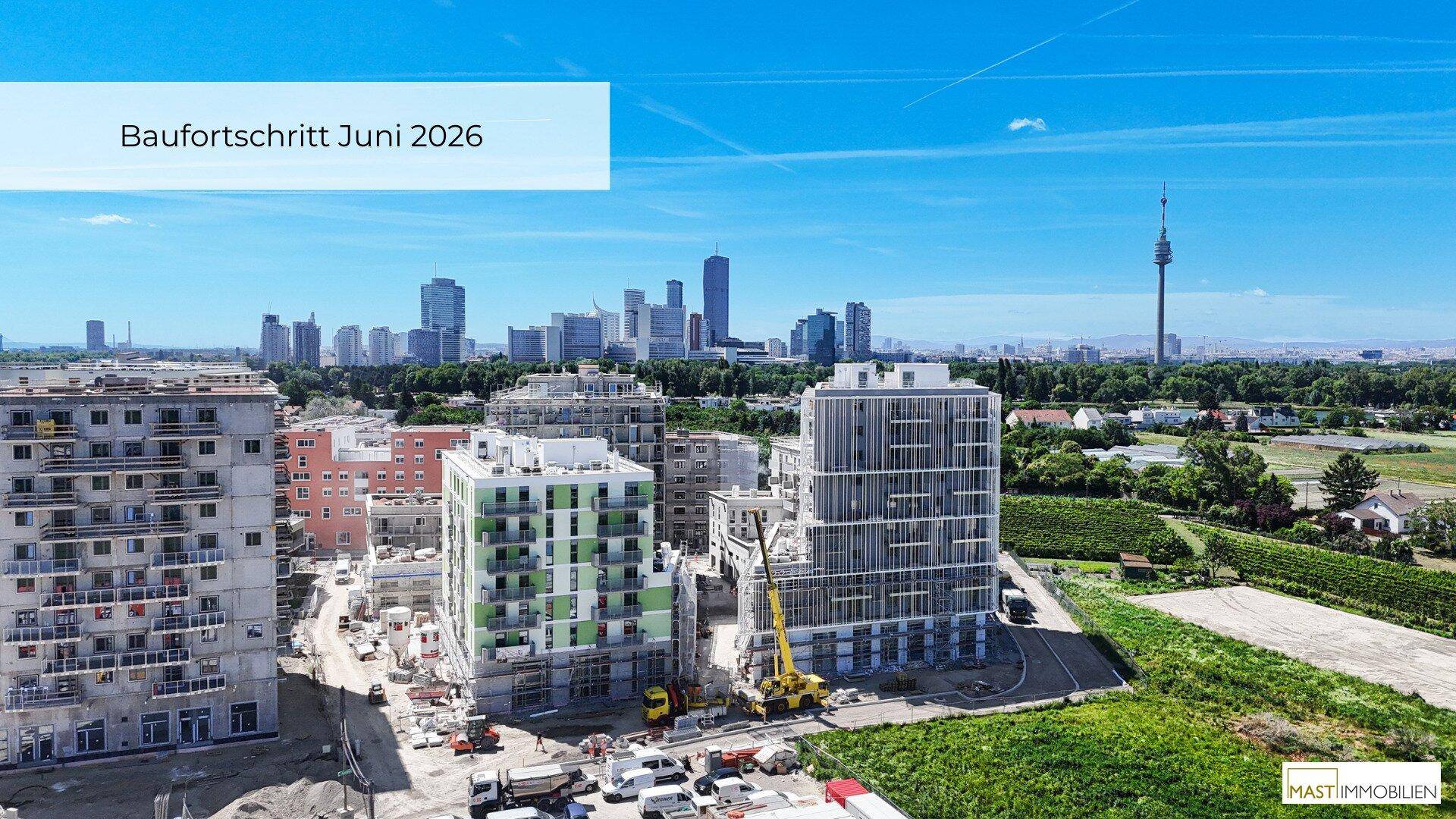 Luftaufnahme des Baufortschritts mit modernen Gebäuden und Blick auf die Wiener Skyline.