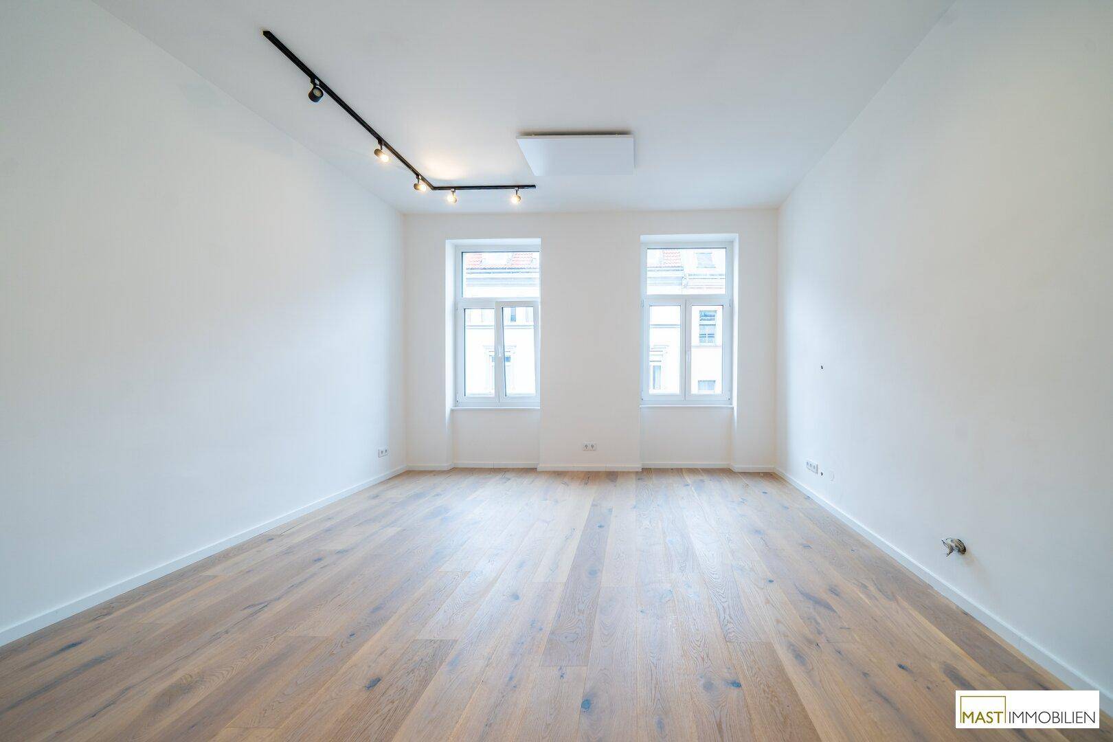 Heller und geräumiger Raum mit neuem Holzboden und moderner Beleuchtung, ideal für vielfältige Nutzung.
