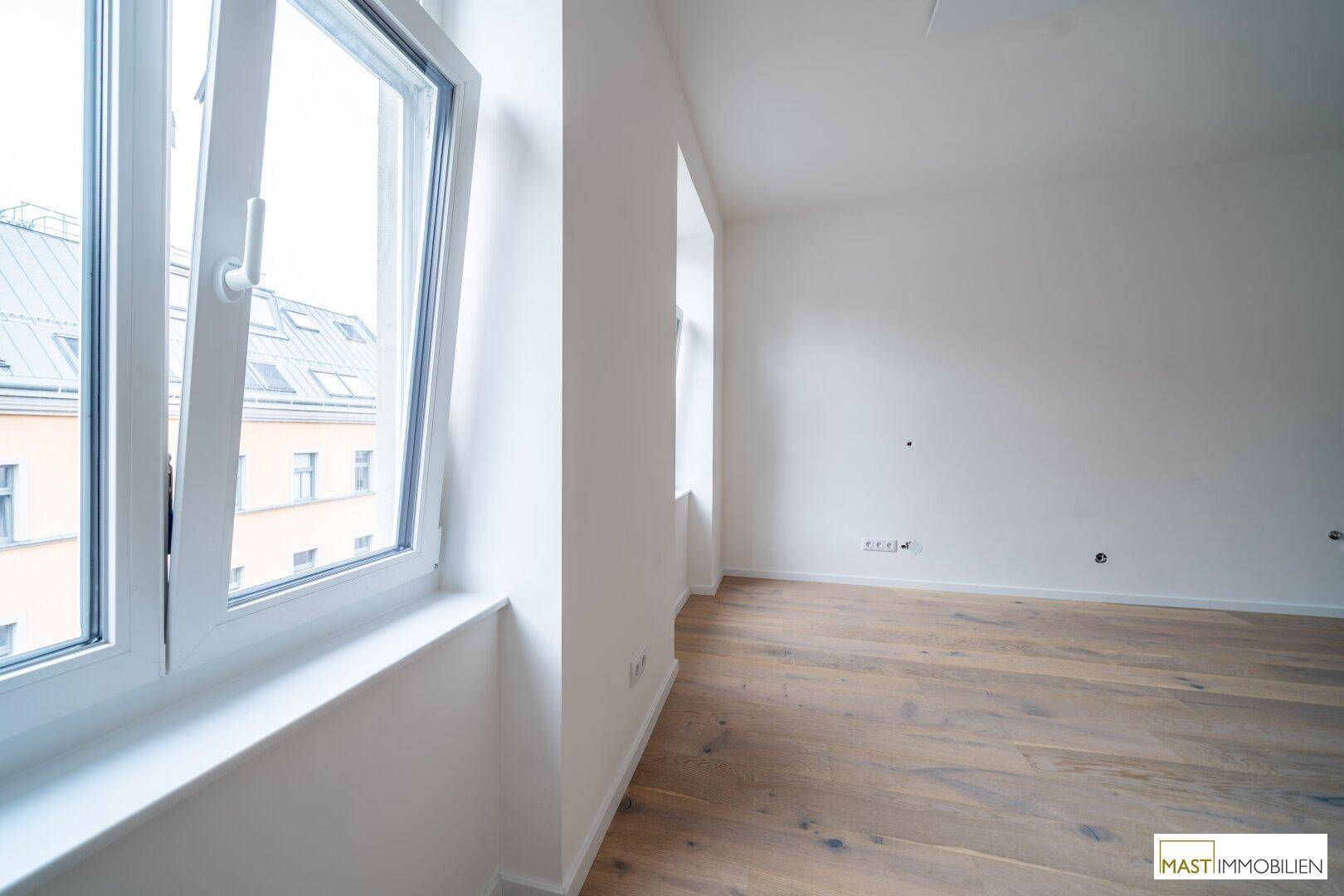 Großes Fenster in einem hellen Raum mit Blick auf die umliegenden Gebäude.