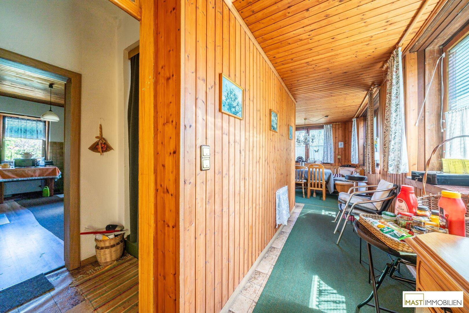 Langer Flur mit Holzvertäfelung an Wänden und Decke, der zu weiteren Räumen führt.