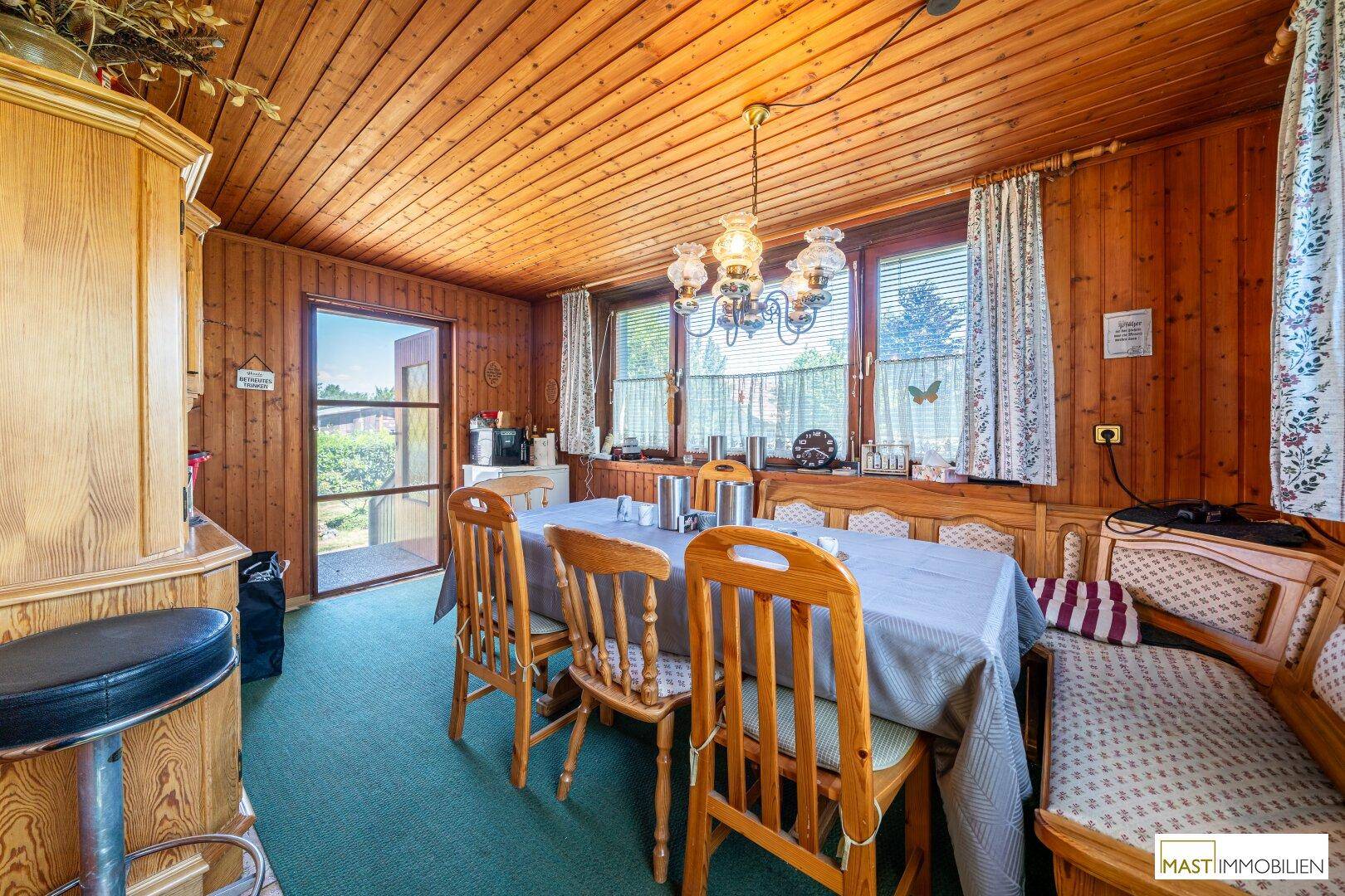 Gemütlicher Essbereich mit Holztisch, Bänken und Stühlen, umgeben von Holzvertäfelung.