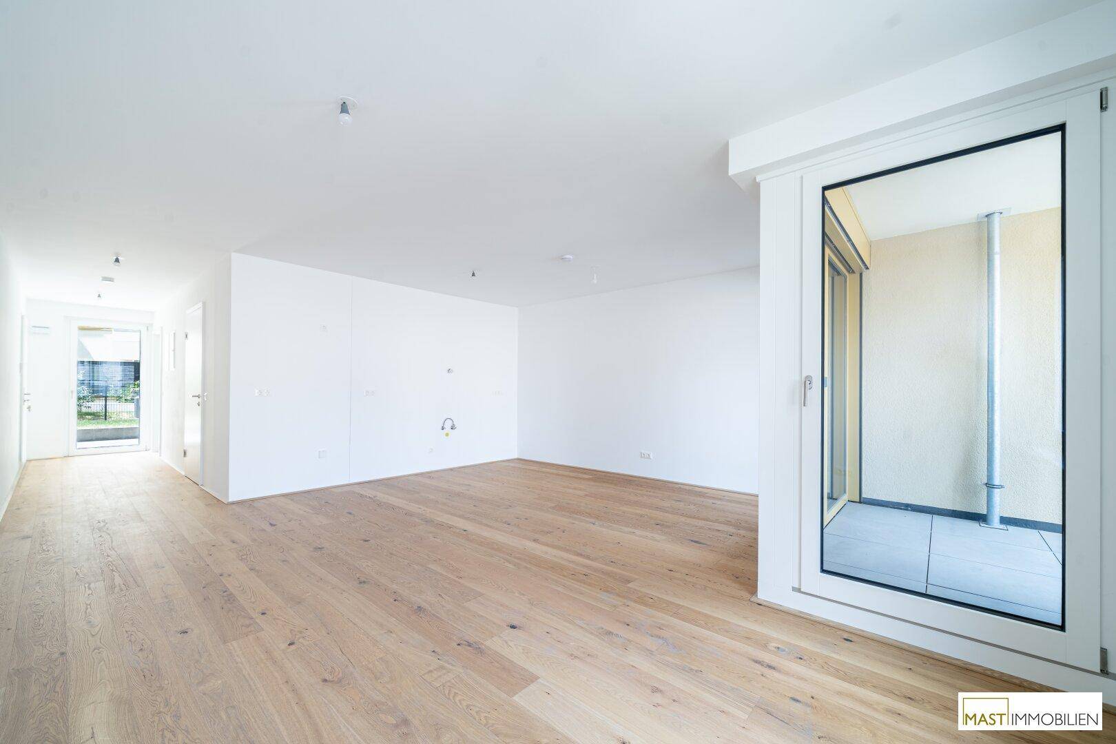 Geräumiges, helles Wohnzimmer mit Parkettboden und Zugang zu einem Balkon oder einer Loggia.
